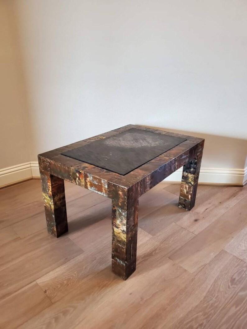 Paul Evans (1931-1987) American Brutalist industrial modern welded steel, copper, mixed metals patchwork coffee table with rivet accents and inset slate stone rectangular top. Circa 1970

Dimensions:
18