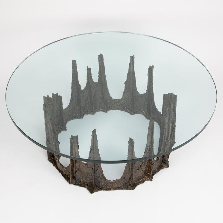 A sculpted bronze and glass “Stalagmite” coffee table, the thick round glass top sits on top of a bronze base, decorated with thick impasto like application of bronze over an iron framework. A magnificent example of Paul Evans’ sculptural work – a