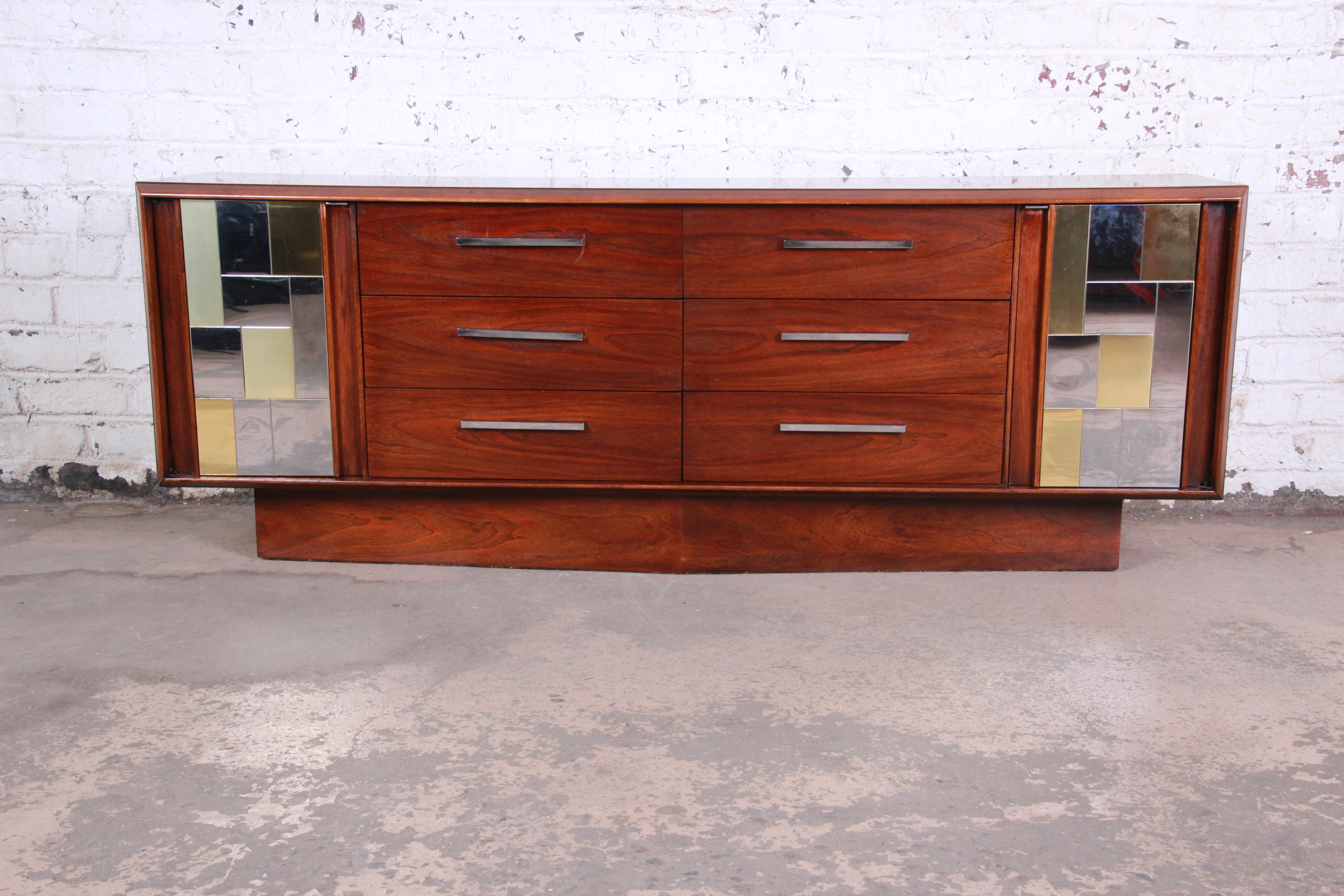 An exceptional Mid-Century Modern long dresser or credenza by Lane Furniture in the style of the Cityscape line by Paul Evans. The credenza features gorgeous walnut wood grain, with a unique patchwork design in chrome and brass. It offers ample