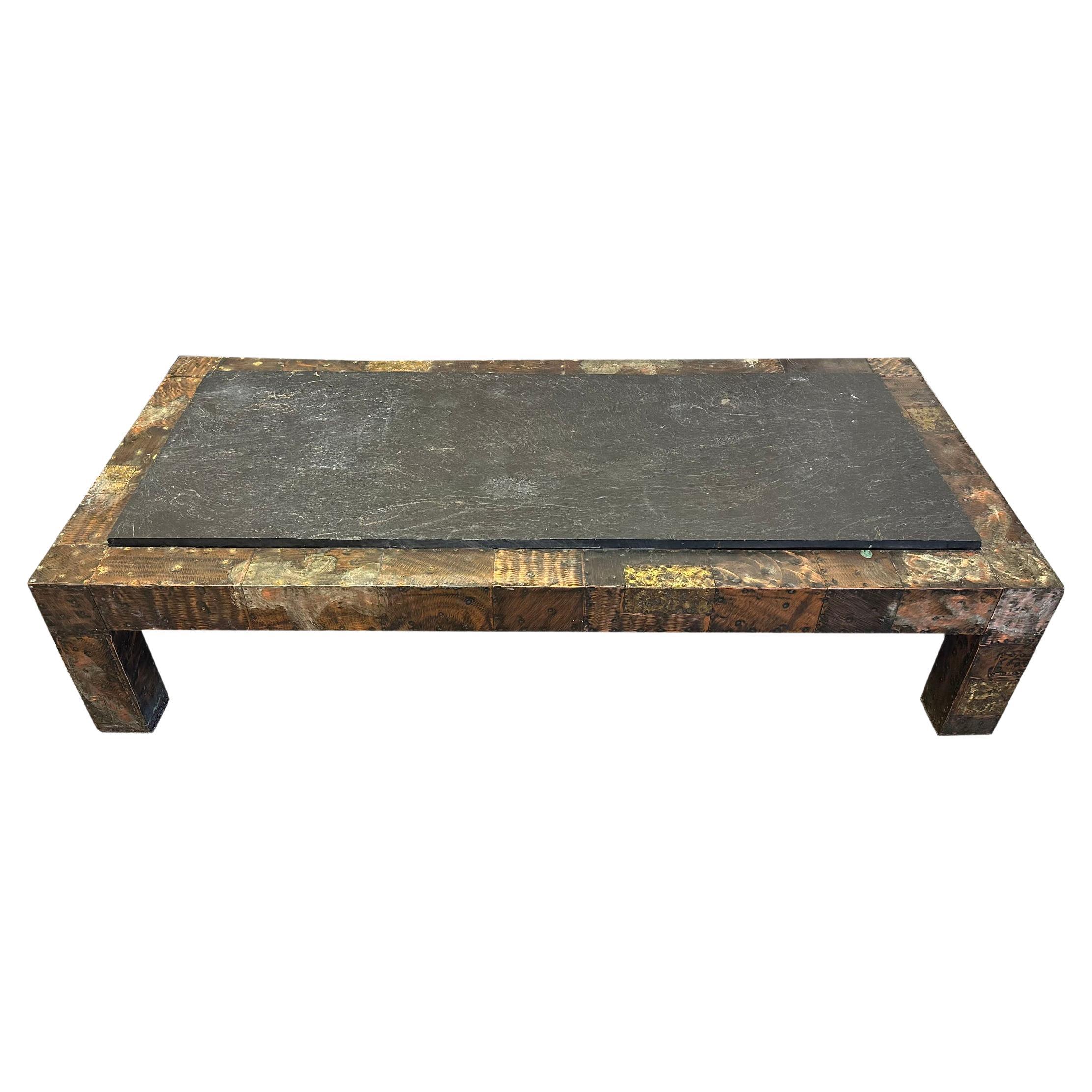 A metal Brutalist patchwork coffee table with slate top designed by the American designer Paul Evans (1931-1987) for Directional. This substantial coffee table is made from a wooden base with a mixed metal patchwork design wrapped over the wood. A