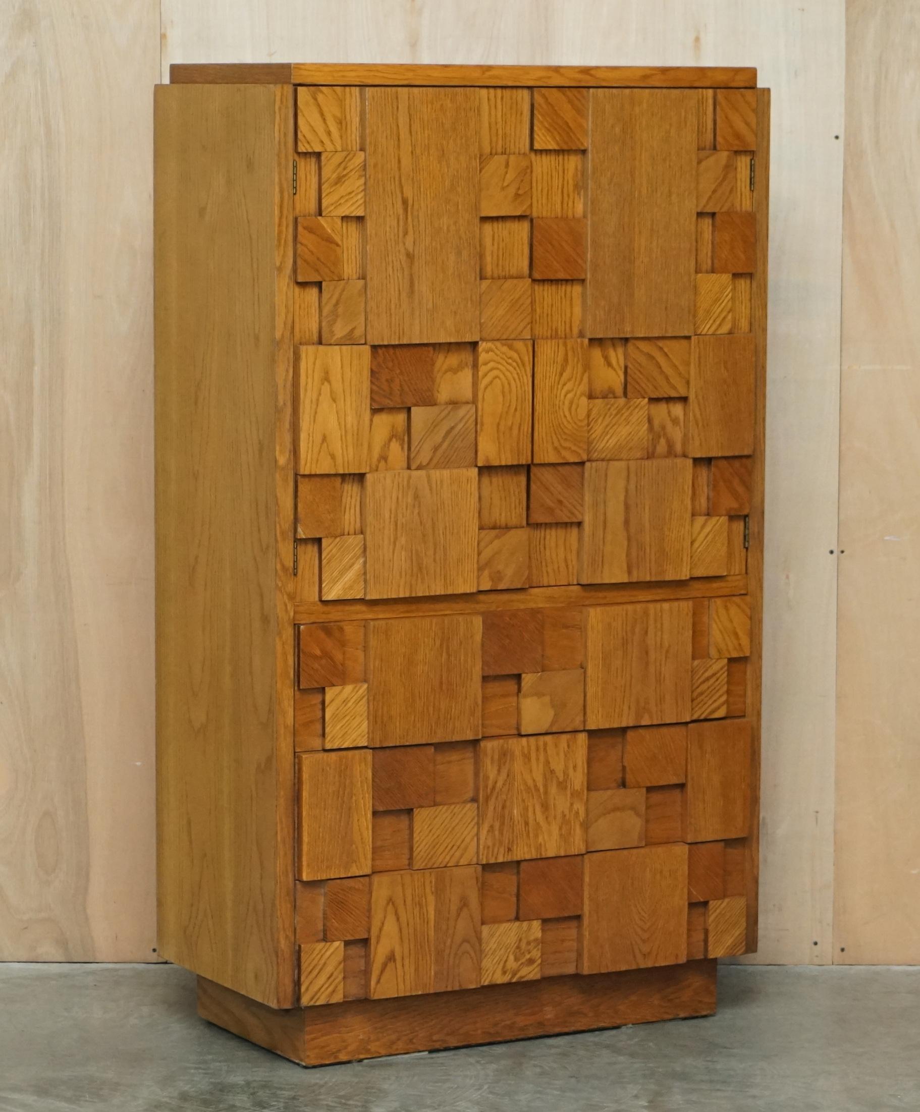 We are delighted to offer for sale this stunning original Paul Evans designed for Lane Furniture, Brutalist cupboard with chest of drawers base which is part of a suite

Paul Evans was an American furniture designer and sculptor known for his