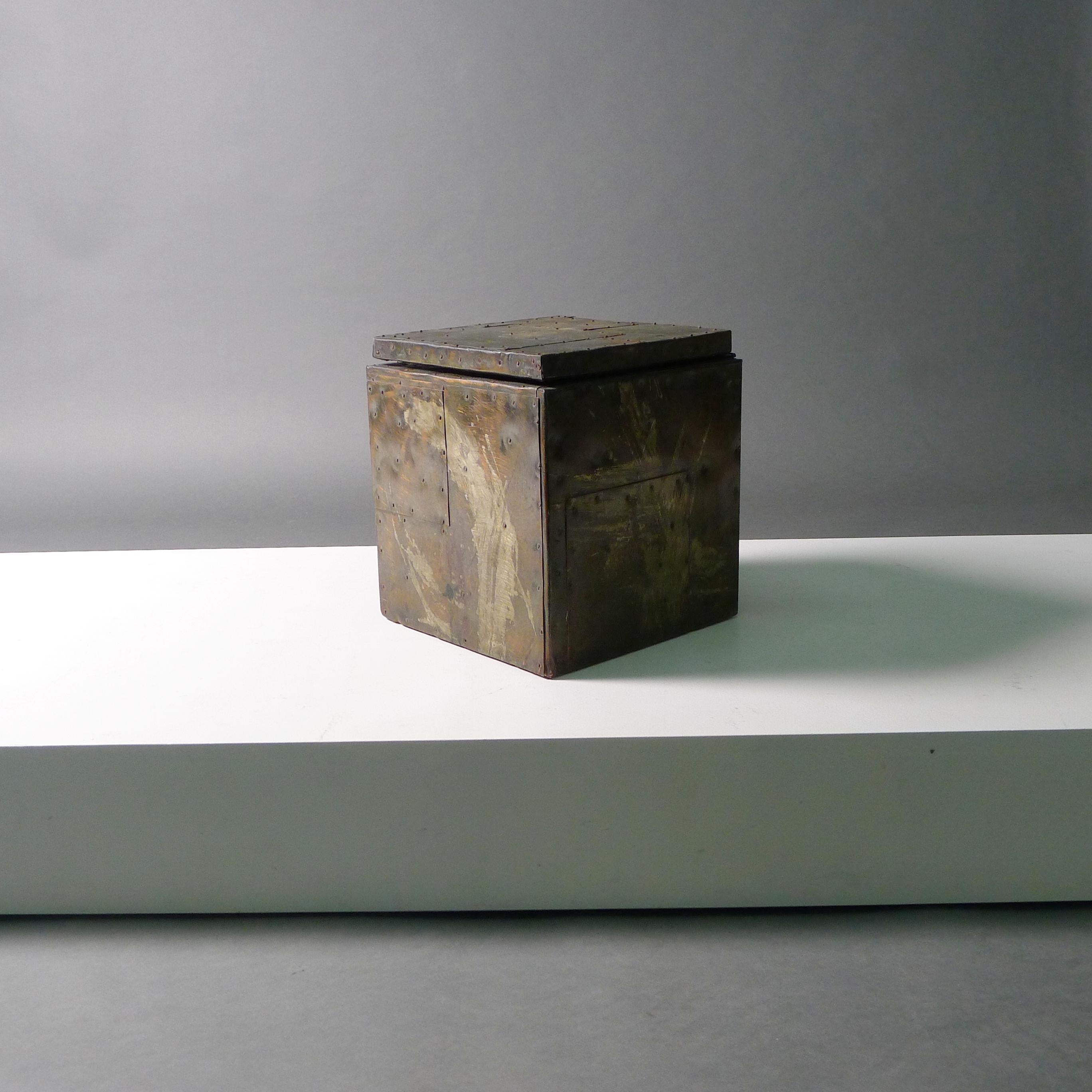 Brutalist 'patchwork' ice bucket, circa 1970, by Paul Evans.

Constructed from patinated and hammered metals riveted over a plywood frame, with hinged lid and white plastic liner.

28.5cm high, 25.5cm wide, 25.5cm deep