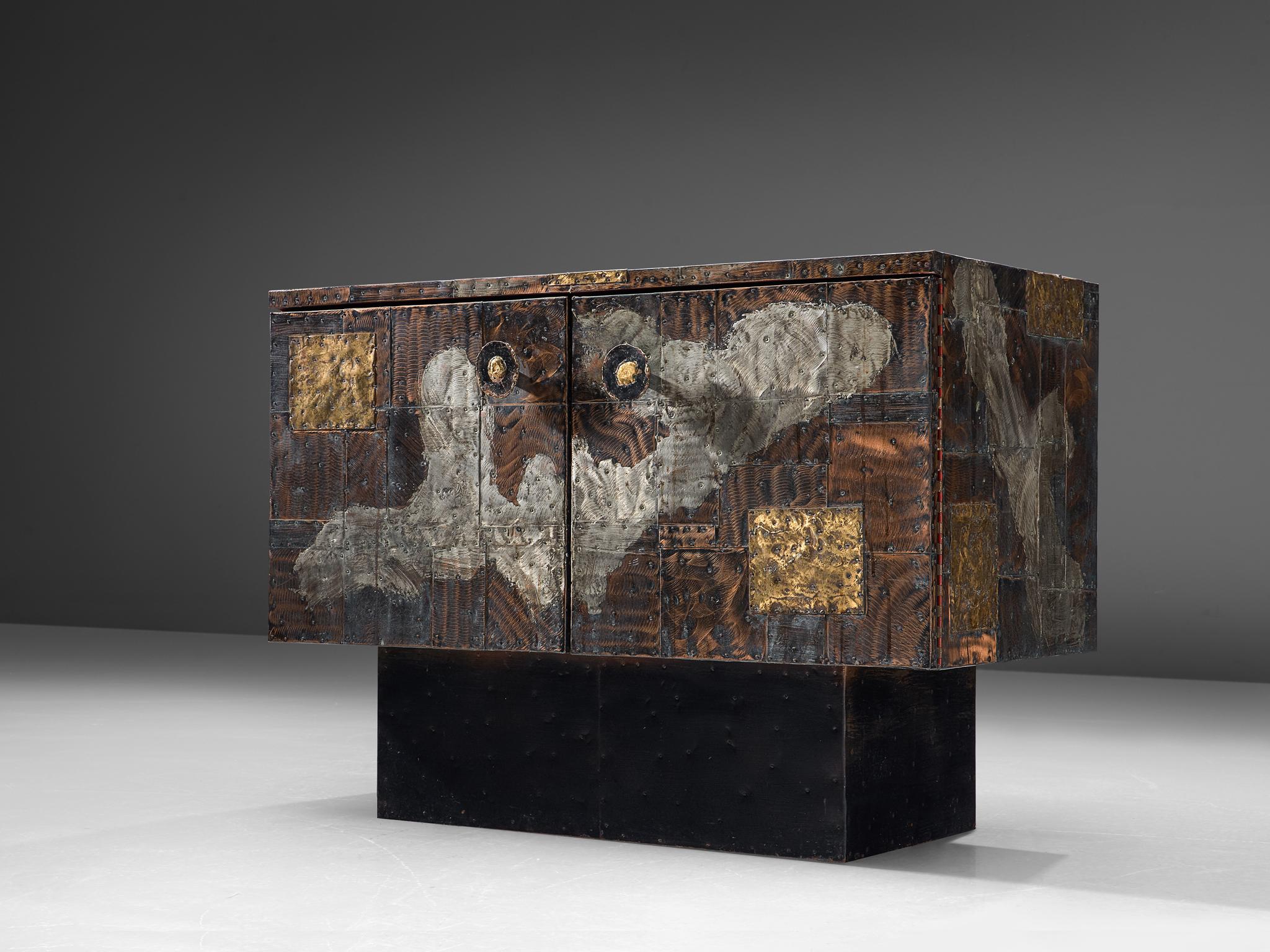 Paul Evans Studio for Directional, patchwork cabinet model PE-302, patinated copper, steel, brass, slate, United States, circa 1960.

Raw and robust small sideboard designed and produced by Paul Evans for Directional furniture. The wheeled sideboard