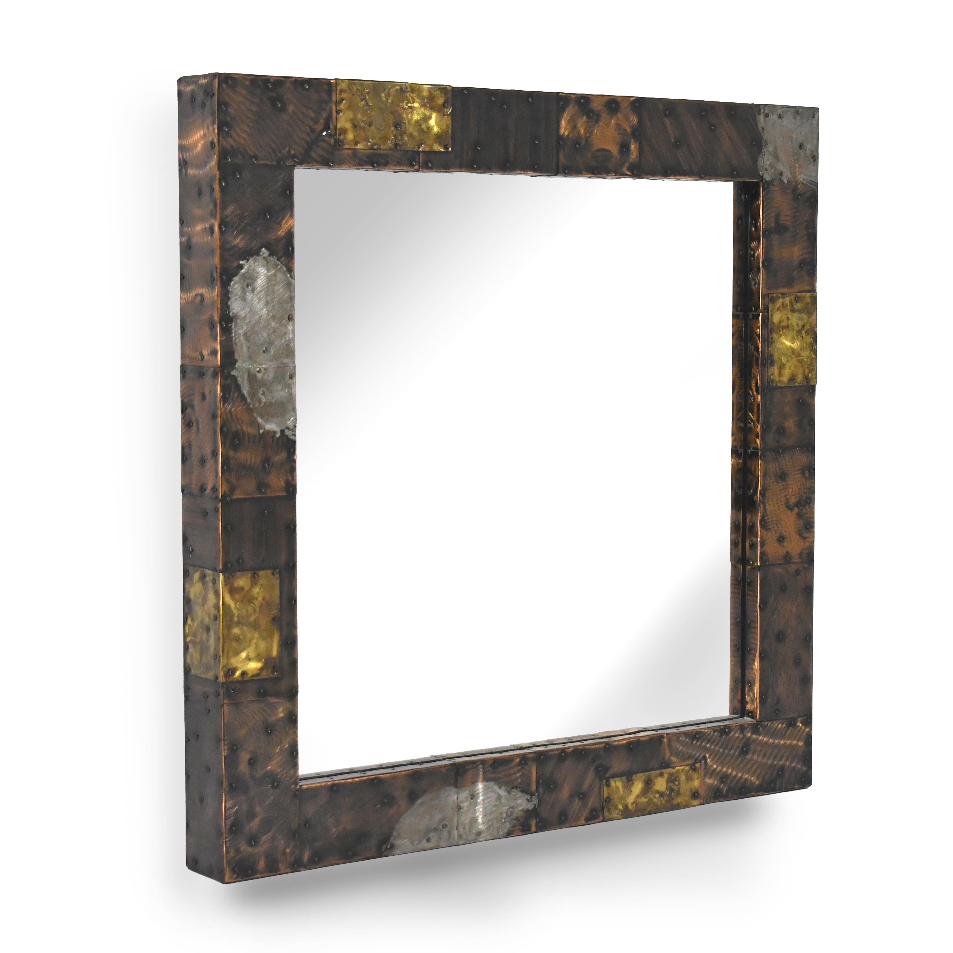 This striking 1968 wall-mounted mirror by Paul Evans is from his copper, bronze and pewter patchwork series. The hammered and heavily worked squares of copper and bronze give an architectural geometry which is broken up by pewter applied in bold