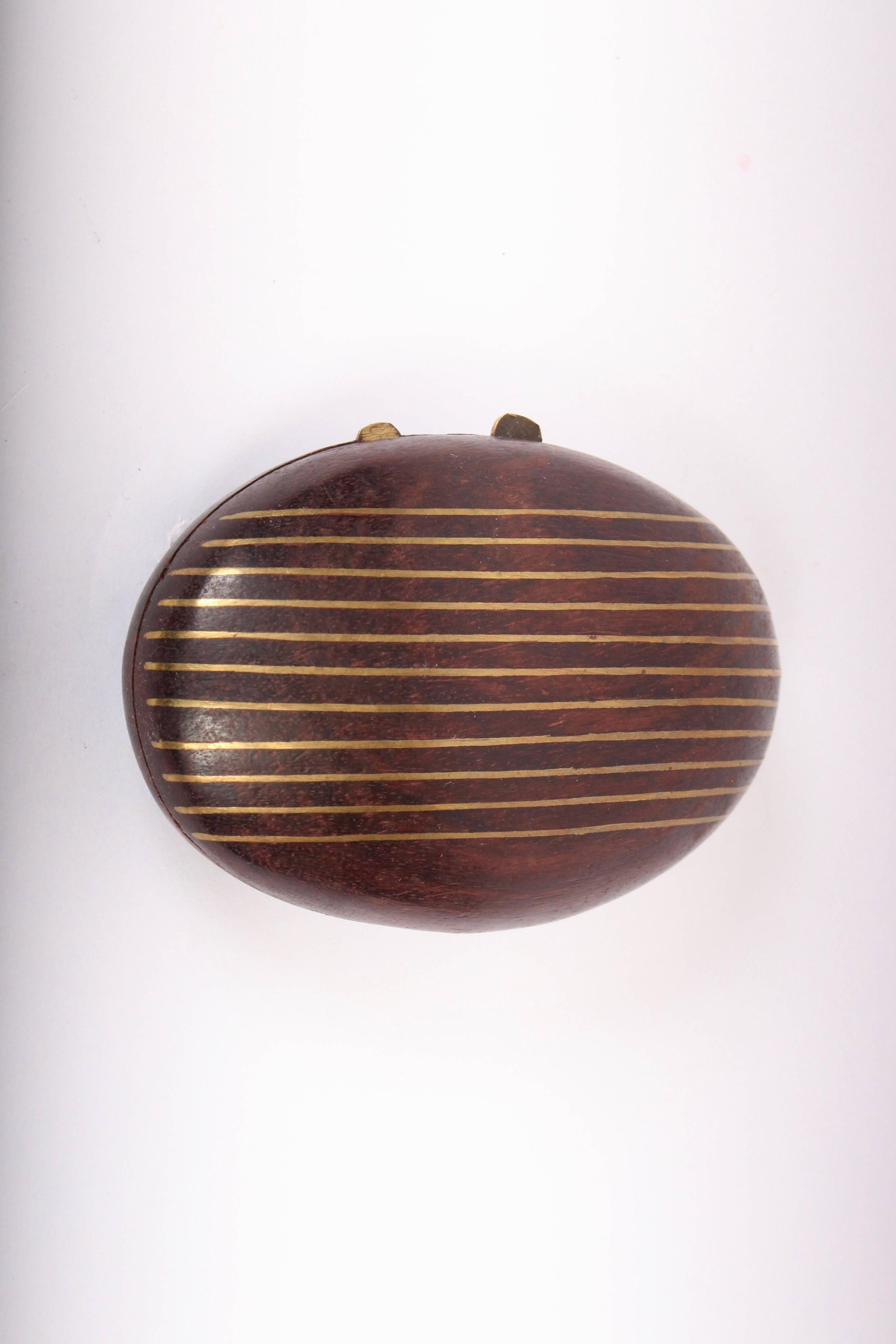 American mid century rosewood and brass inlay small oval accessory box in the style of Paul Evans and Phillip Lloyd, circa 1960. Featuring a handcrafted clam shaped 2-piece smooth dark grain rosewood box, banded with horizontal brass inlay. Detailed