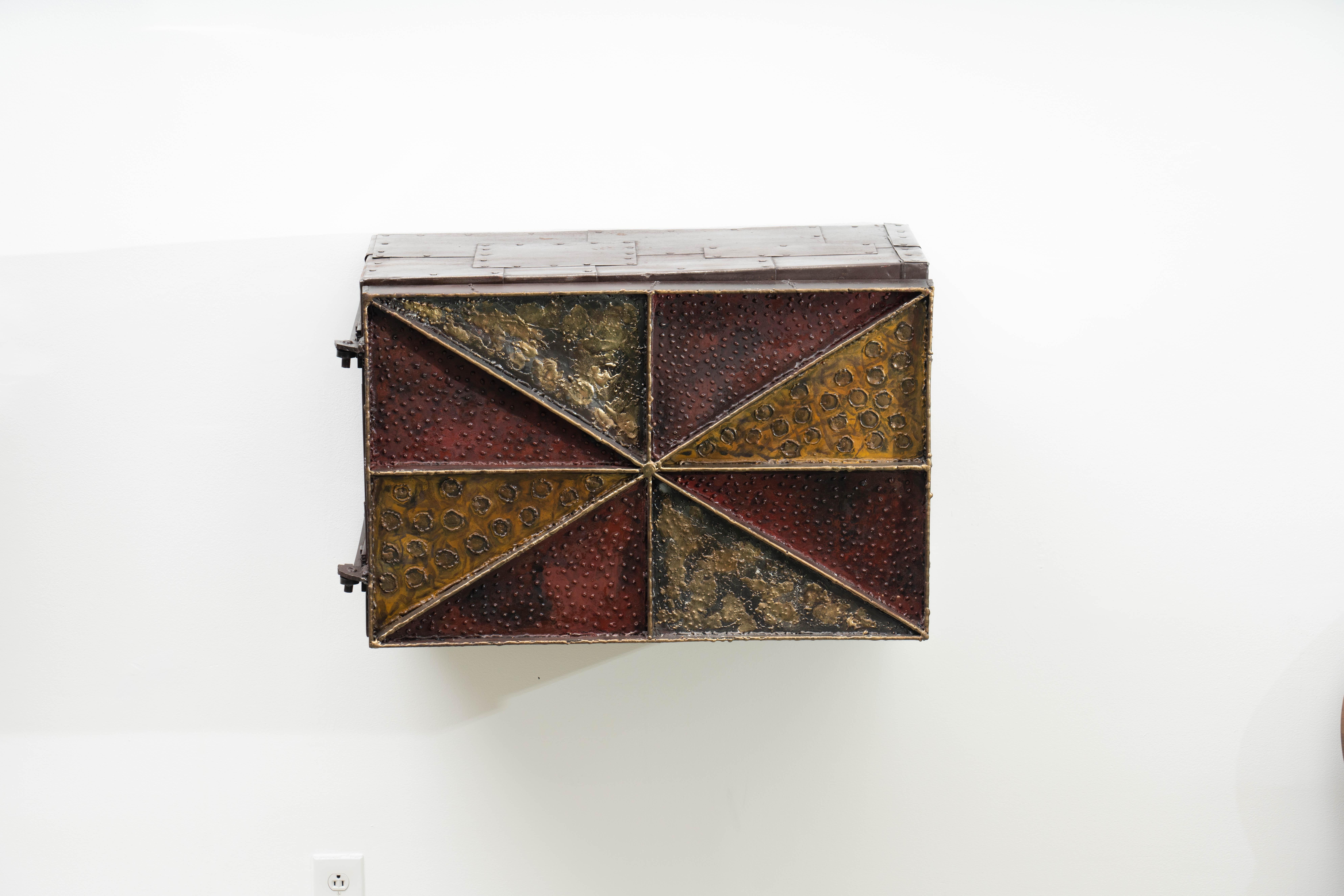 Despite the accessible size and lively surface decoration, very few of this style cabinet were produced by the Paul Evans Studio. With the same welded steel frame in a radial diamond pattern and patchwork steel sides, each were individually