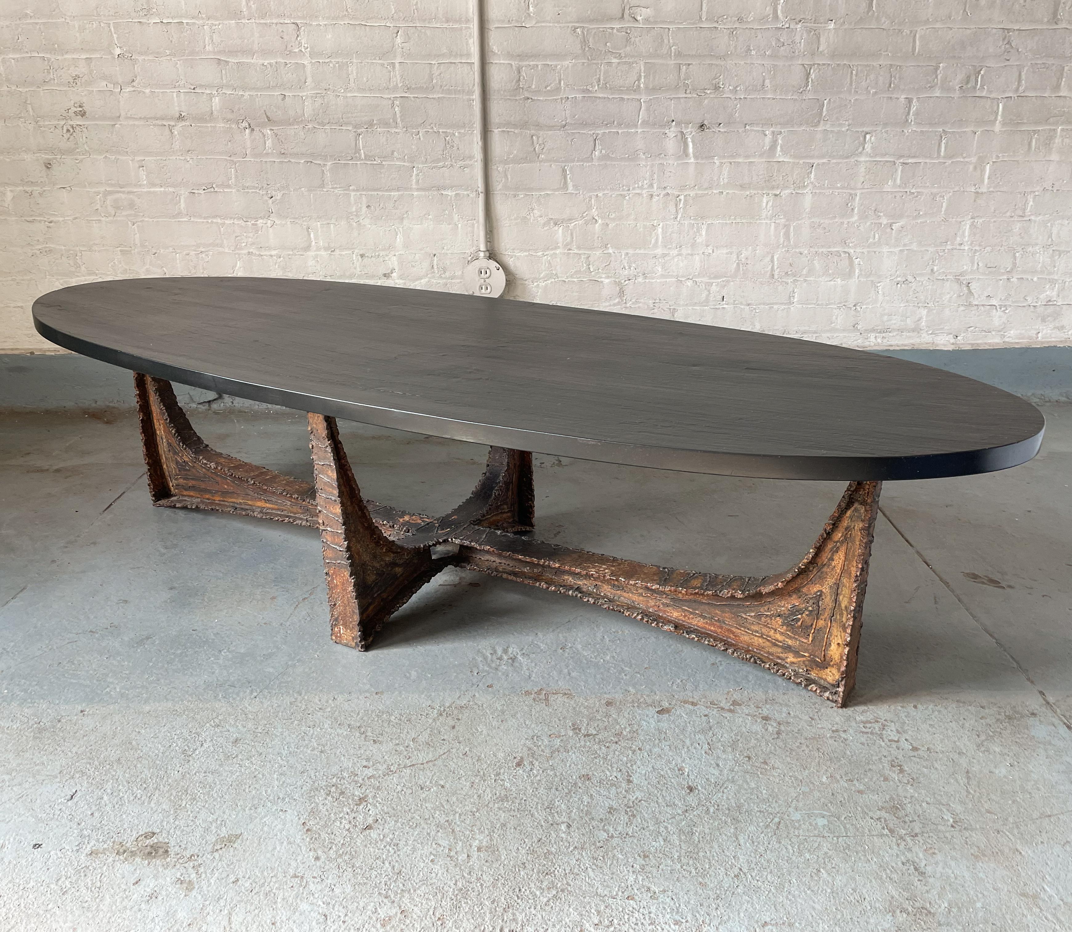 A rare Paul Evans coffee table with an elliptical slate top and a welded and patinated steel base, produced by Paul Evans Studio circa 1965. The base, with its arched cruciform shape, has an almost bridge-like architectural bearing. The heavy slate