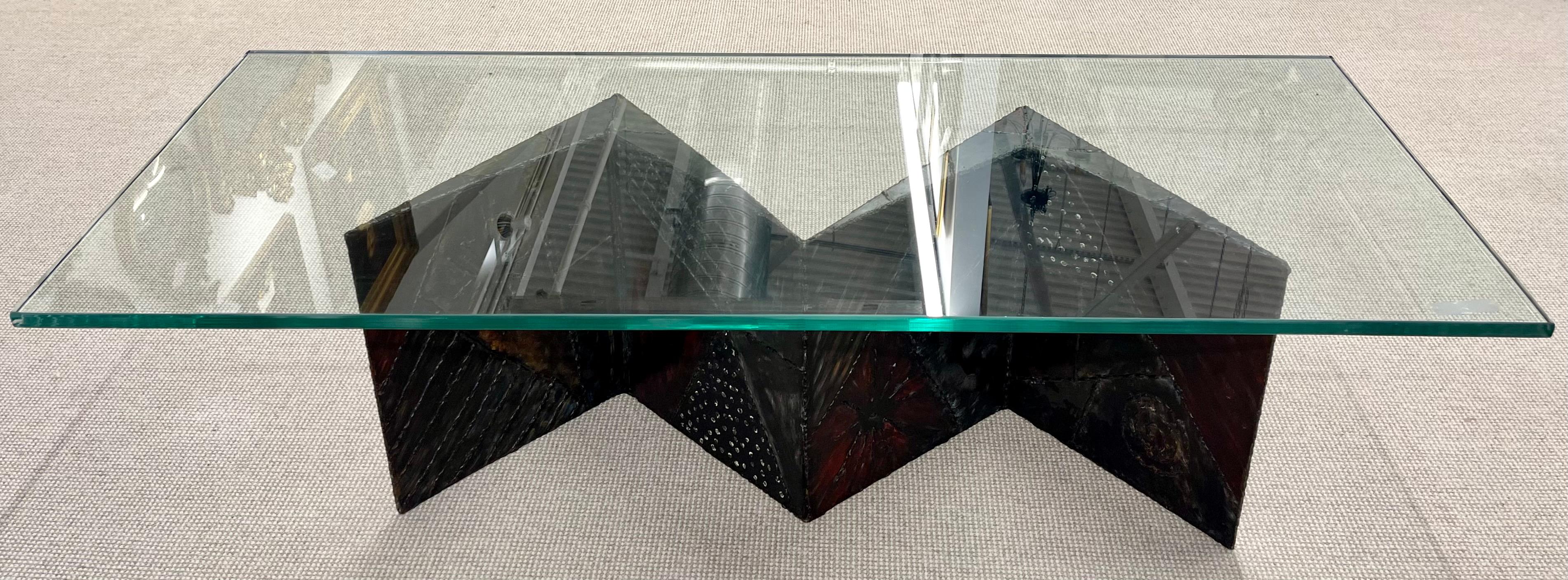 Table basse à nœud papillon de style Paul Evans avec plateau en verre. Une base en métal finement construite en forme de nœud papillon supporte un épais plateau en verre rectangulaire. Initiales en relief PE11. Peut-être de Paul Evans.