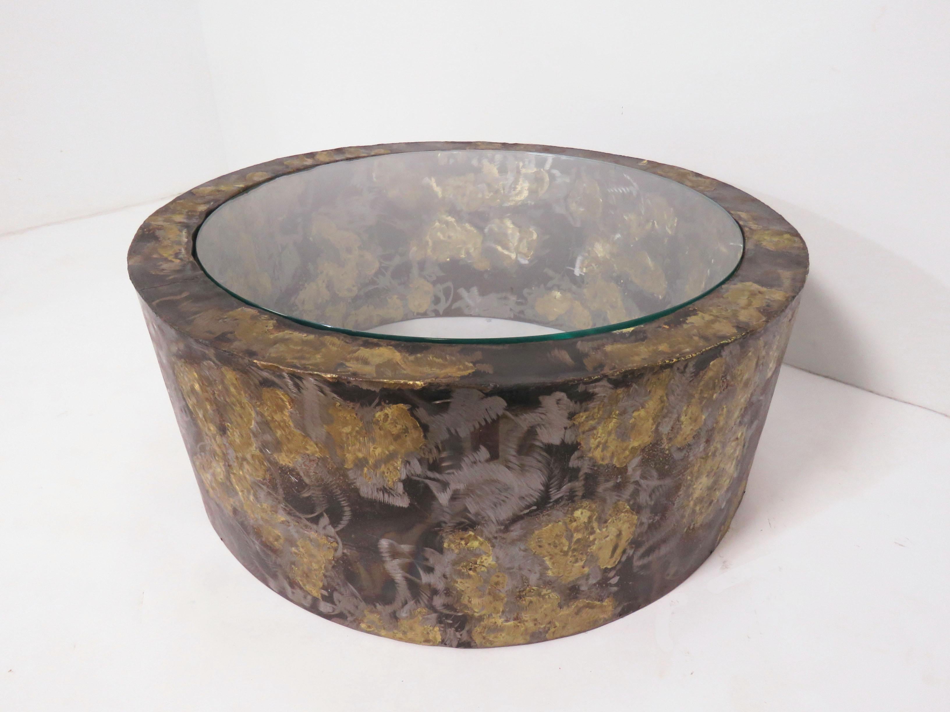 Brutalist drum shaped coffee table in patinated metal with inset glass top, in the manner of Paul Evans, circa 1960s.