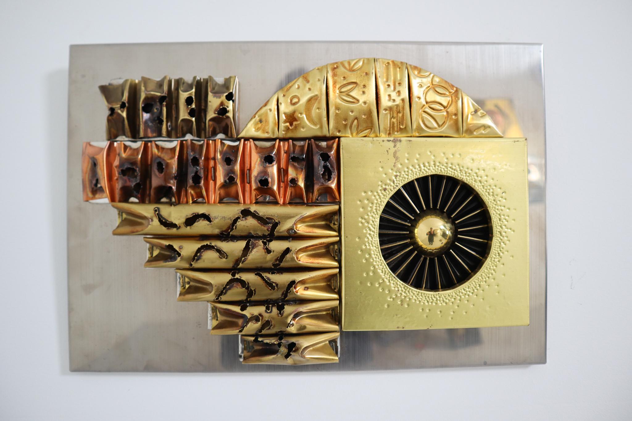 This brutalist wall sculpture is inspired and in the style of sculptor Paul Avans made approximately 1970, Europe . This abstract wall sculpture consist of tortured copper and brass in abstract shapes. The wall sculpture is affixed to a wood board