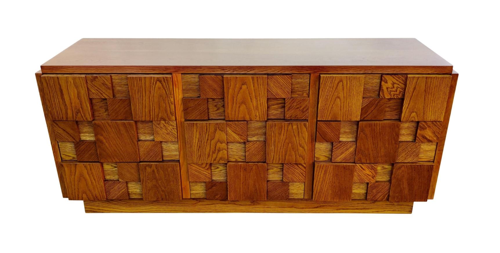 This dresser was designed in the brutalist style made iconic by Paul Evans. Made with tens of blocks of walnut attached to the front, it lends an imposing and dark look while retaining the rich color of the walnut. The dresser sports 9 expansive