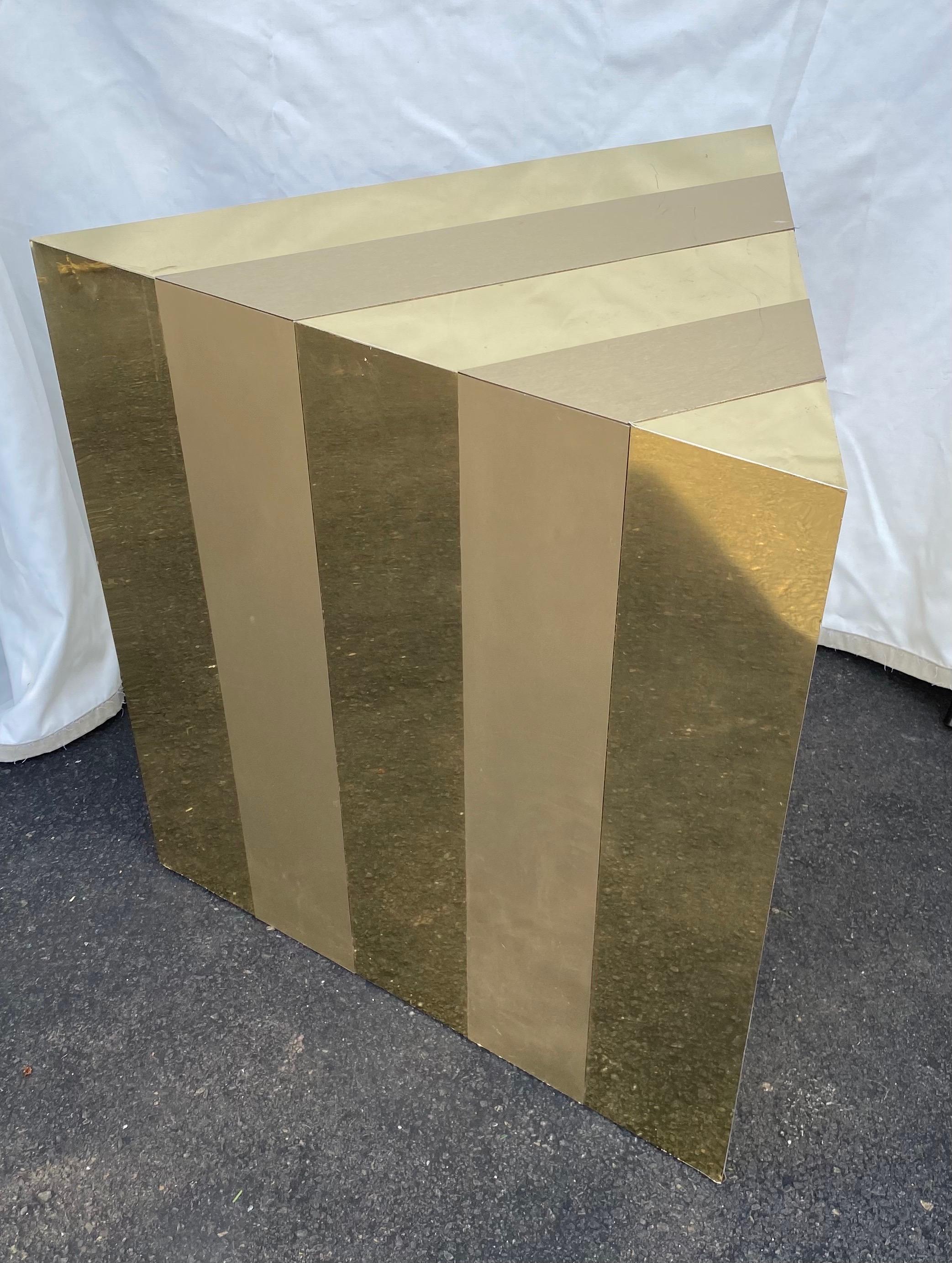 Graphic Mid-Century Modern Paul Evans style end or side table, circa 1970's. This sculptural geometric triangle shaped accent table features a striking polished and matte gold metal clad vertical directional striped city scape design. A versatile