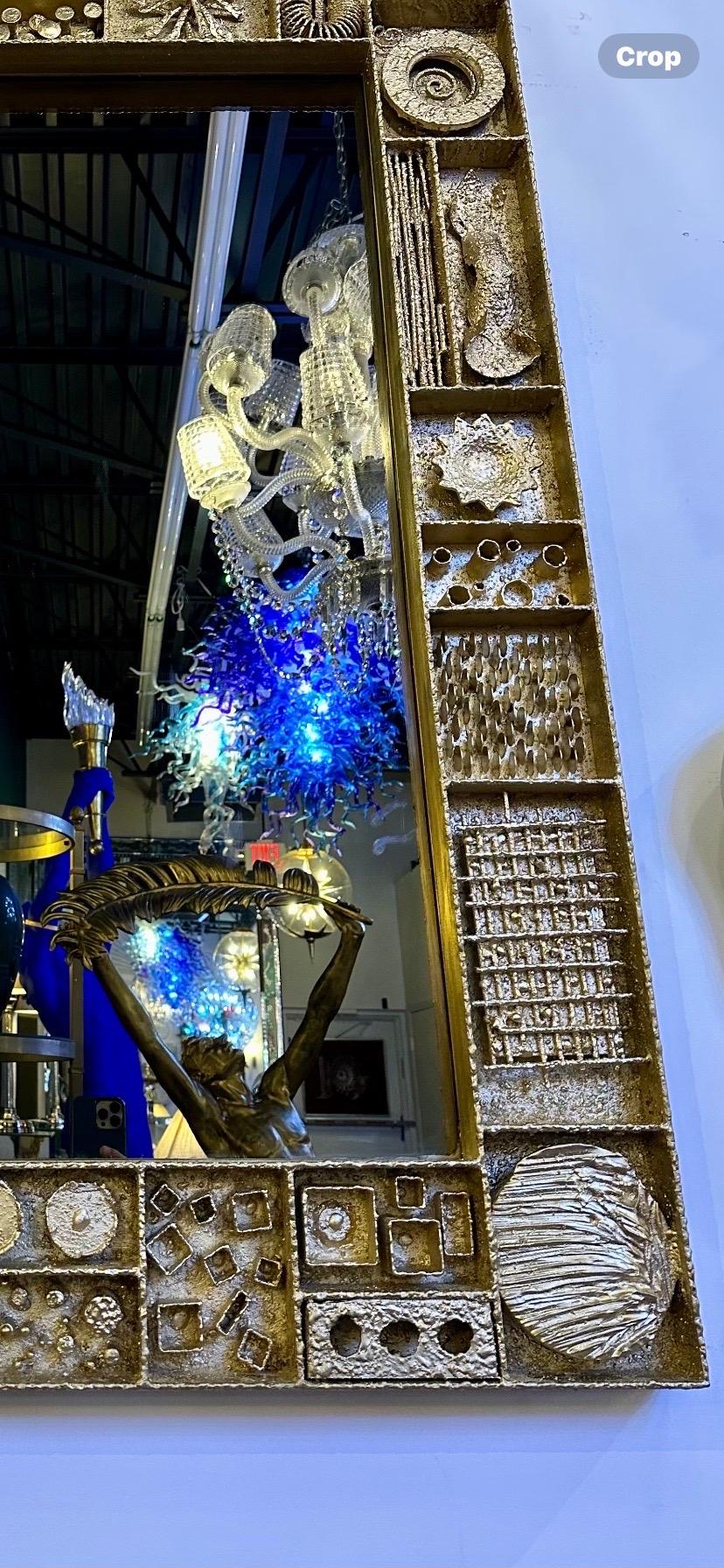 Specchio in stile Paul Evans, metalli misti scolpiti. Grande specchio da parete con supporto in legno e lavorazione a mano, decorato con una varietà di motivi astratti in rilievo dorati.