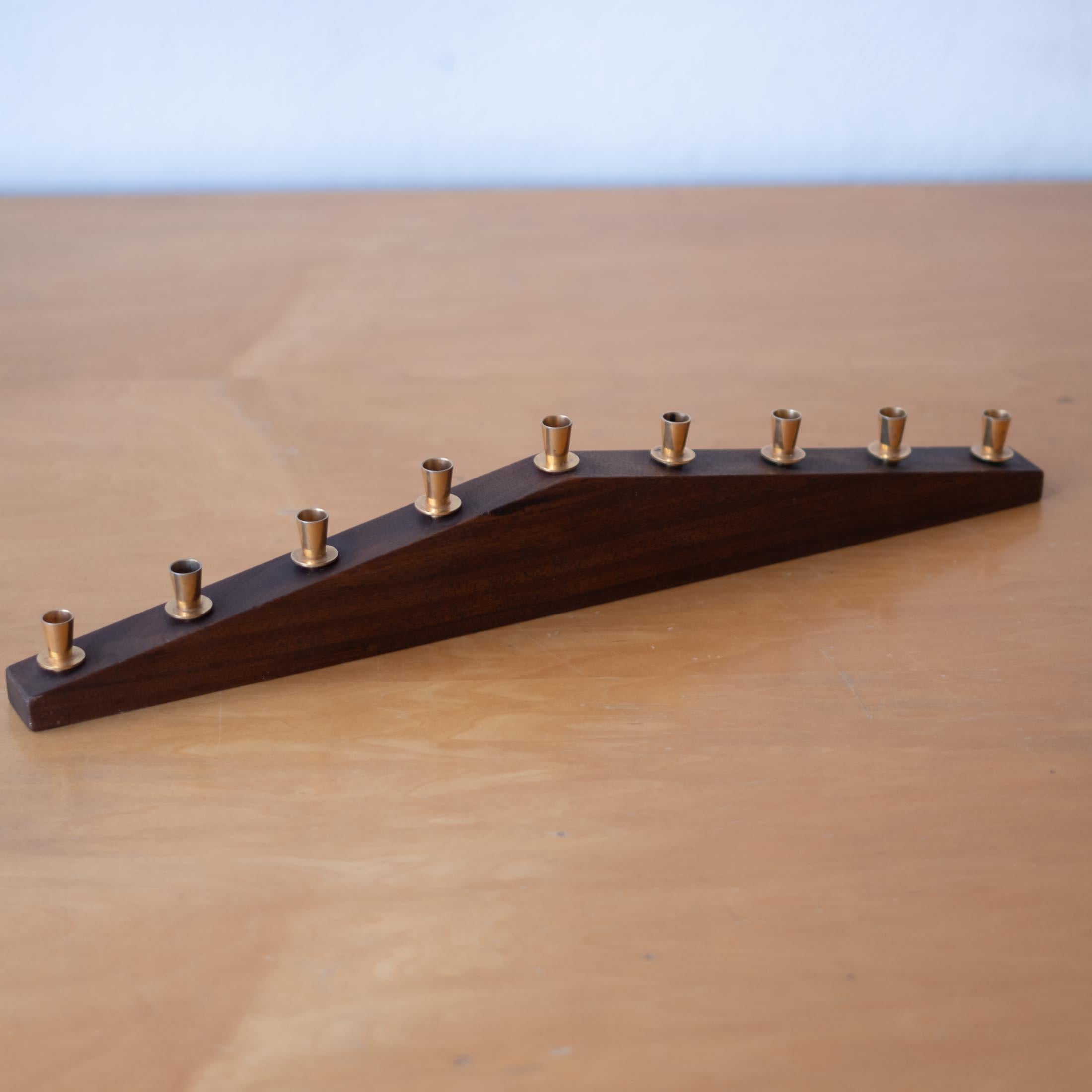 Paul Evans Hanukkah Menorah crafted from walnut with brass candleholders. This is an early work by Paul Evans, dating from 1955.  

His line of menorahs are Illustrated in Paul Evans: Designer and Sculptor, Jeffery Head, p. 19 There were distributed