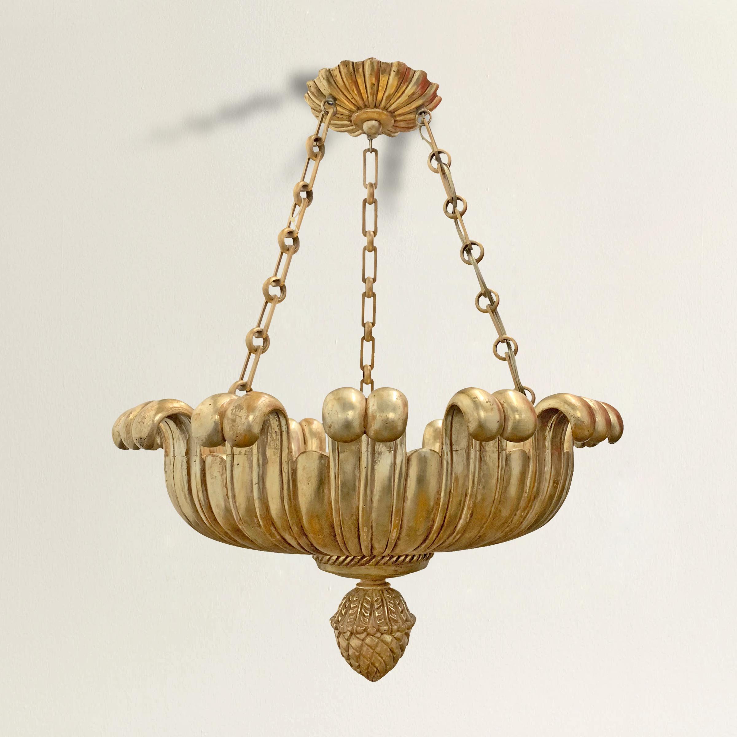 A wonderful contemporary Paul Ferrante carved wood single lotus chandelier with a white gold leaf over red clay finish, hanging from three iron chains and a floral canopy, and ending with a carved wood pineapple finial. The interior has three
