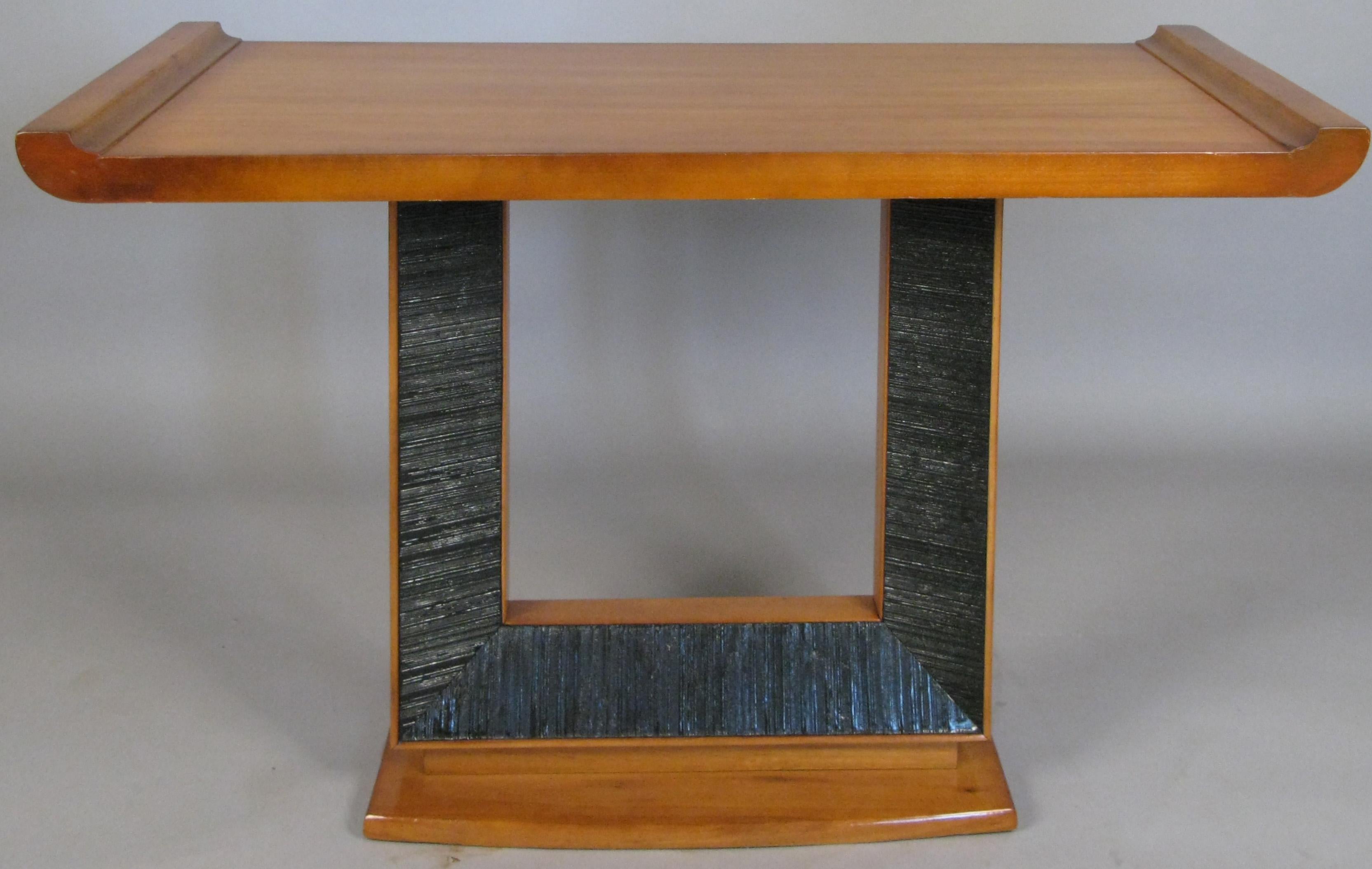 A beautiful 1940s console table designed by Paul Frankl for Brown Saltman, with a flared base, and open center section with ebonized combed detail border, and a wide top surface with raised ends.