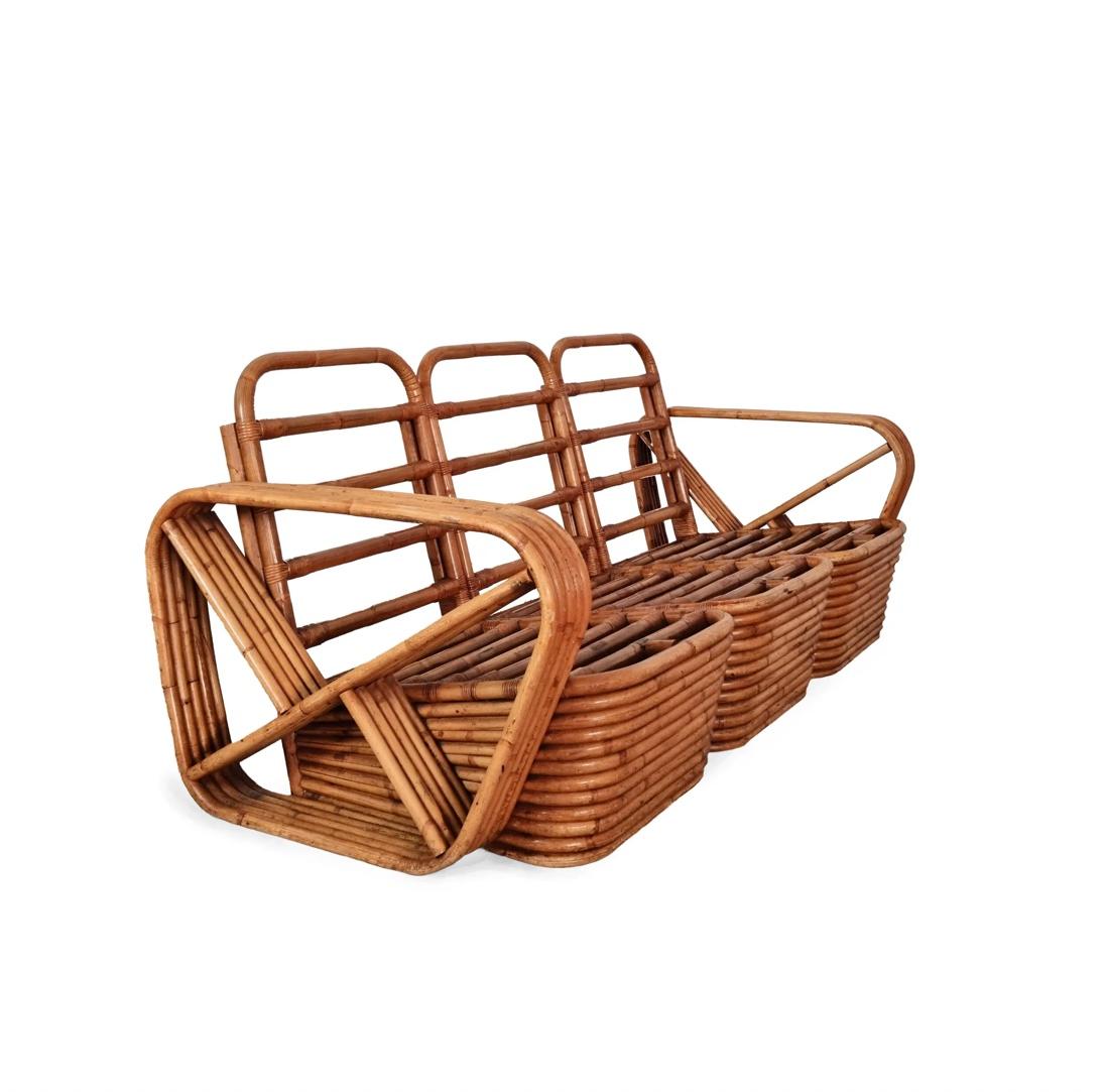 This distinctive 3-seater rattan sofa was designed by Paul Frankl and is known for its striking, looped armrests reminiscent of a pretzel. The sturdy rattan frame and rounded shapes give the piece a unique, playful character. Originally designed in