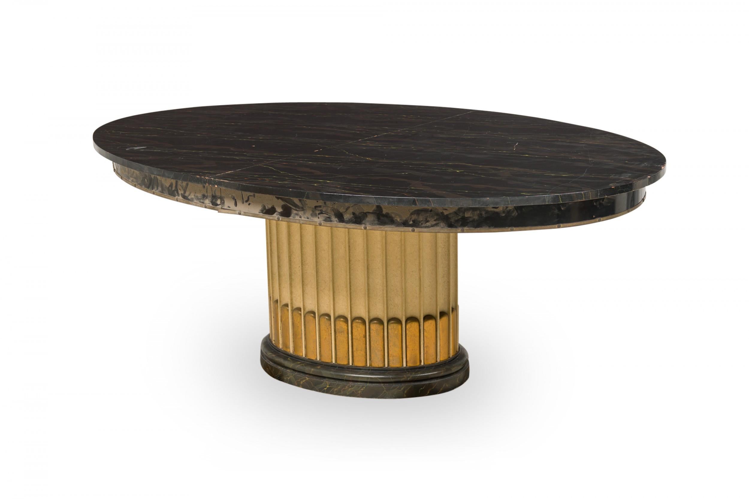 Art Deco American dining table with a black lacquered oval extension top with 2 removable leaves, resting on a fluted column brass and cream painted base. (PAUL FRANKL).