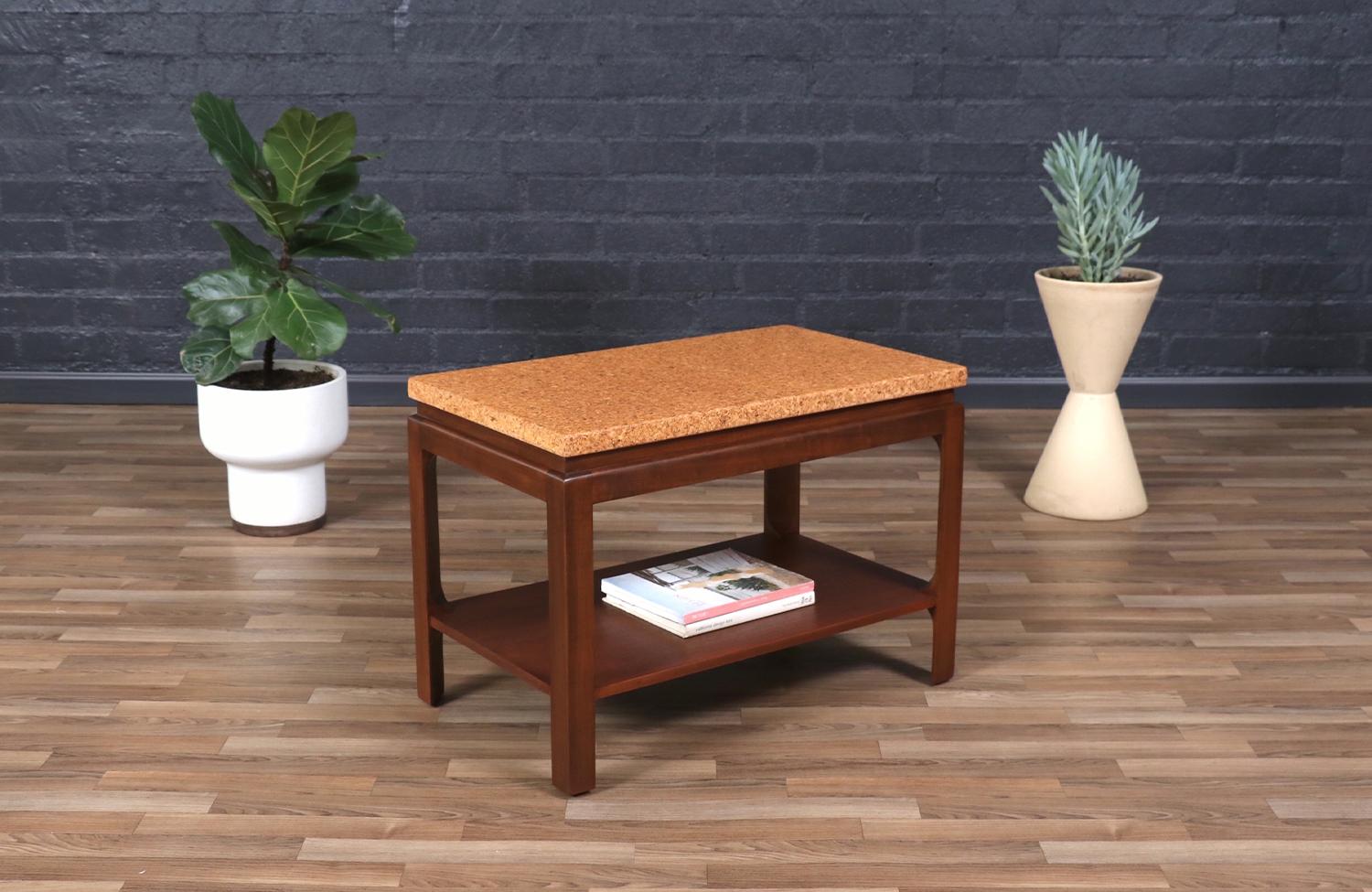 This striking two-tier side table by Paul Frankl for Johnson Furniture is a perfect example of his innovative approach to modern design. Featuring a natural cork top, it offers a beautifully textured contrast against the sleek wooden frame, creating