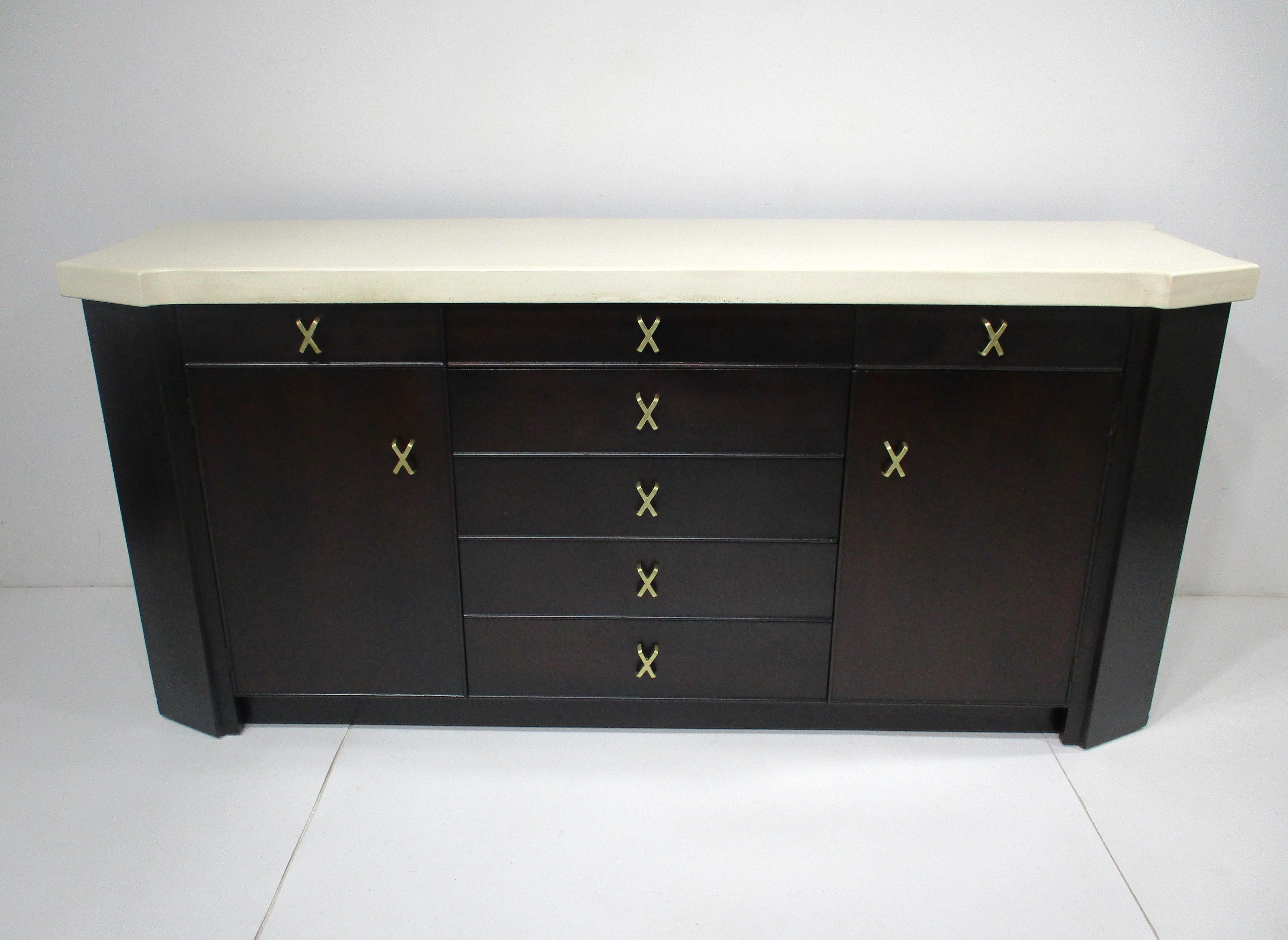 A very well crafted dark ebony toned sideboard with cork top , two doors to each end with a non adjustable shelve , above are two small divided drawers . Solid brass X pulls to the five middle drawers , two small drawers and doors make a statement ,