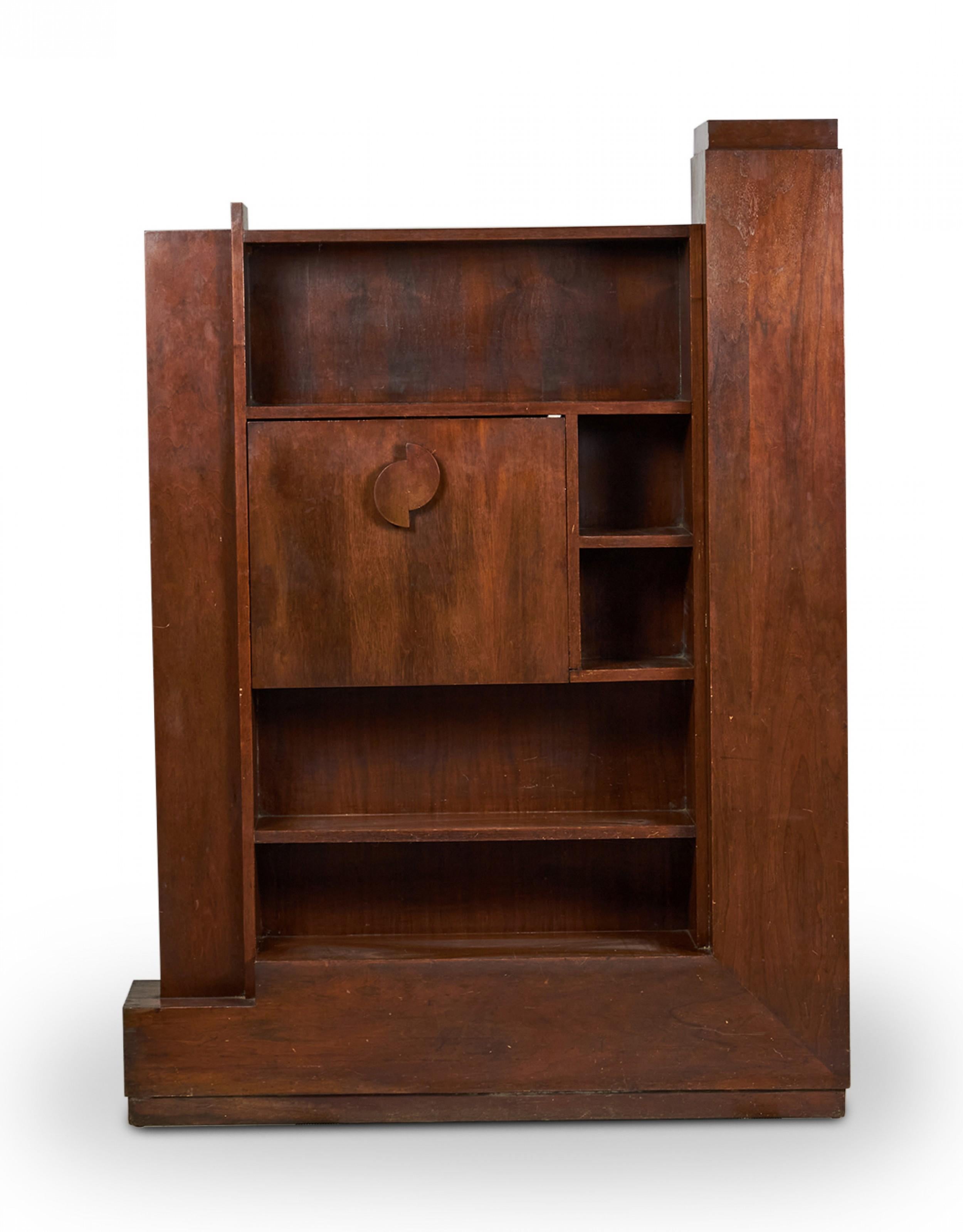 American mid-century walnut fall-front skyscraper desk with a main multi-shelved cabinet flanked on either side by additional shelving units with a central panel that falls forward to create a desktop. (PAUL FRANKL).