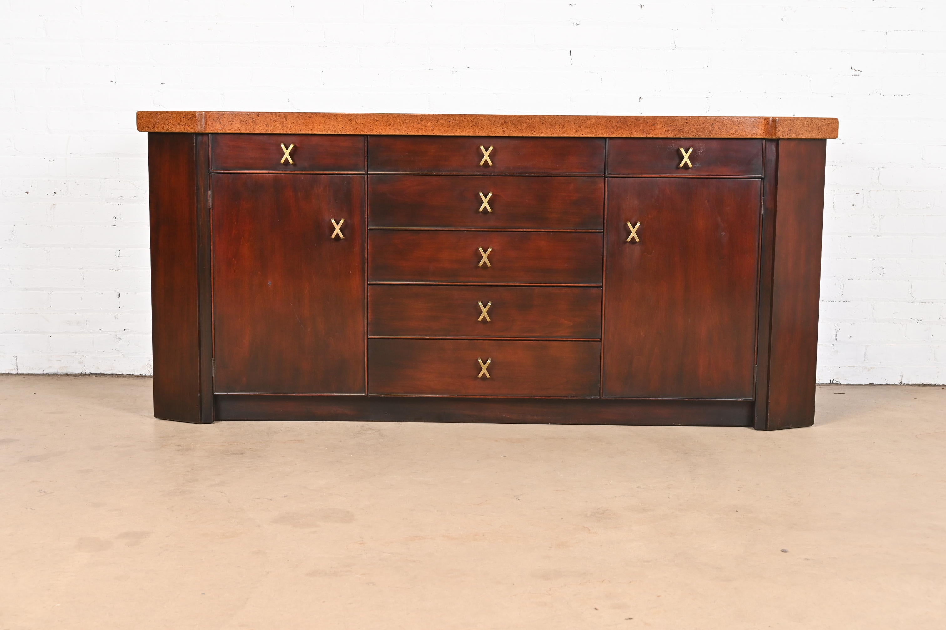 An exceptional Mid-Century Modern sideboard, credenza, or bar cabinet

By Paul Frankl for Johnson Furniture

USA, 1950s

Carved mahogany, with lacquered cork top and iconic brass 
