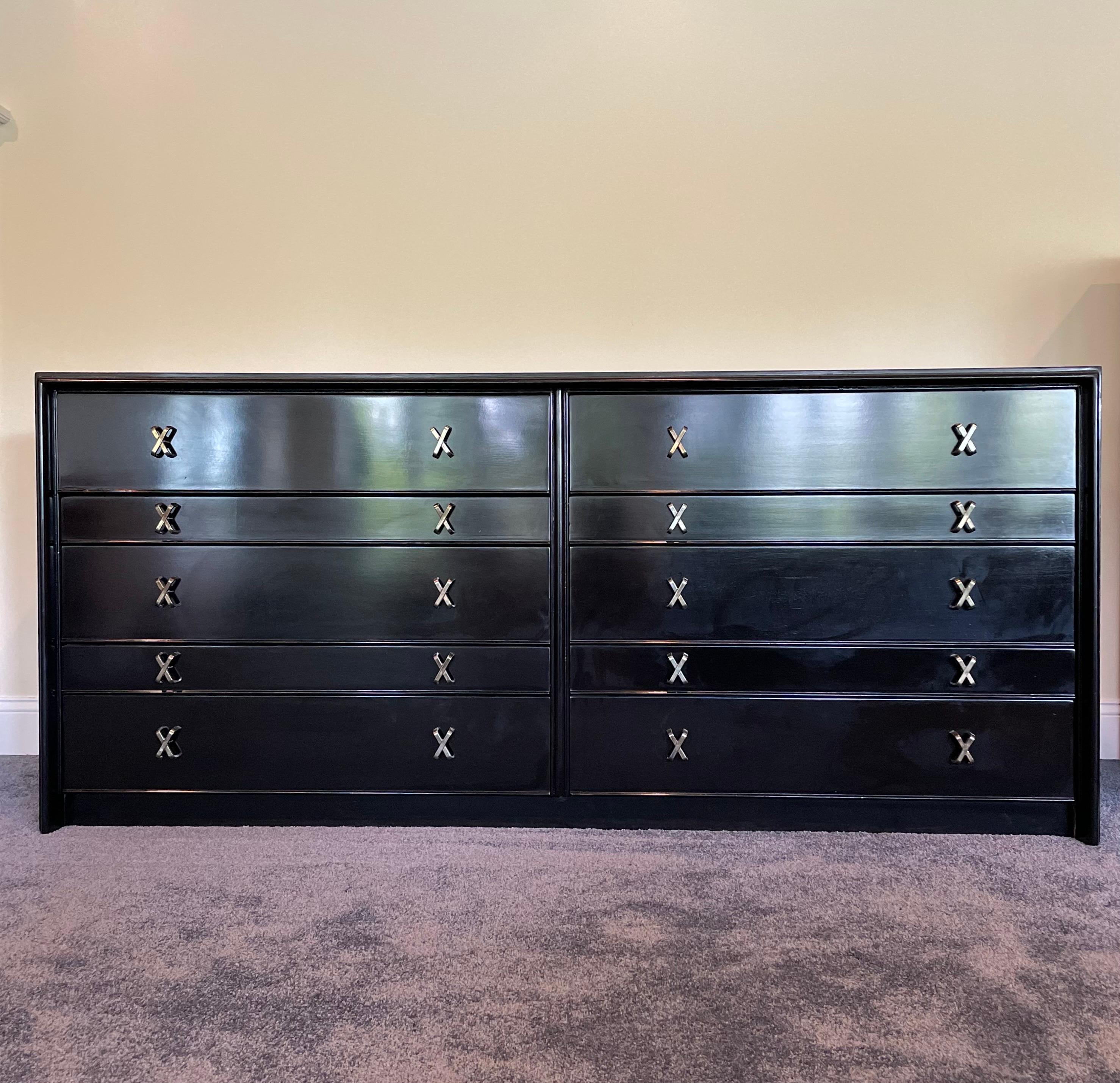A vintage Paul Frankl dresser with iconic brass “x” knobs and newly lacquered black walnut is a truly exceptional piece of furniture. Its clean, angular lines and elegant proportions make it a true statement piece in any room. Sleek, polished, and