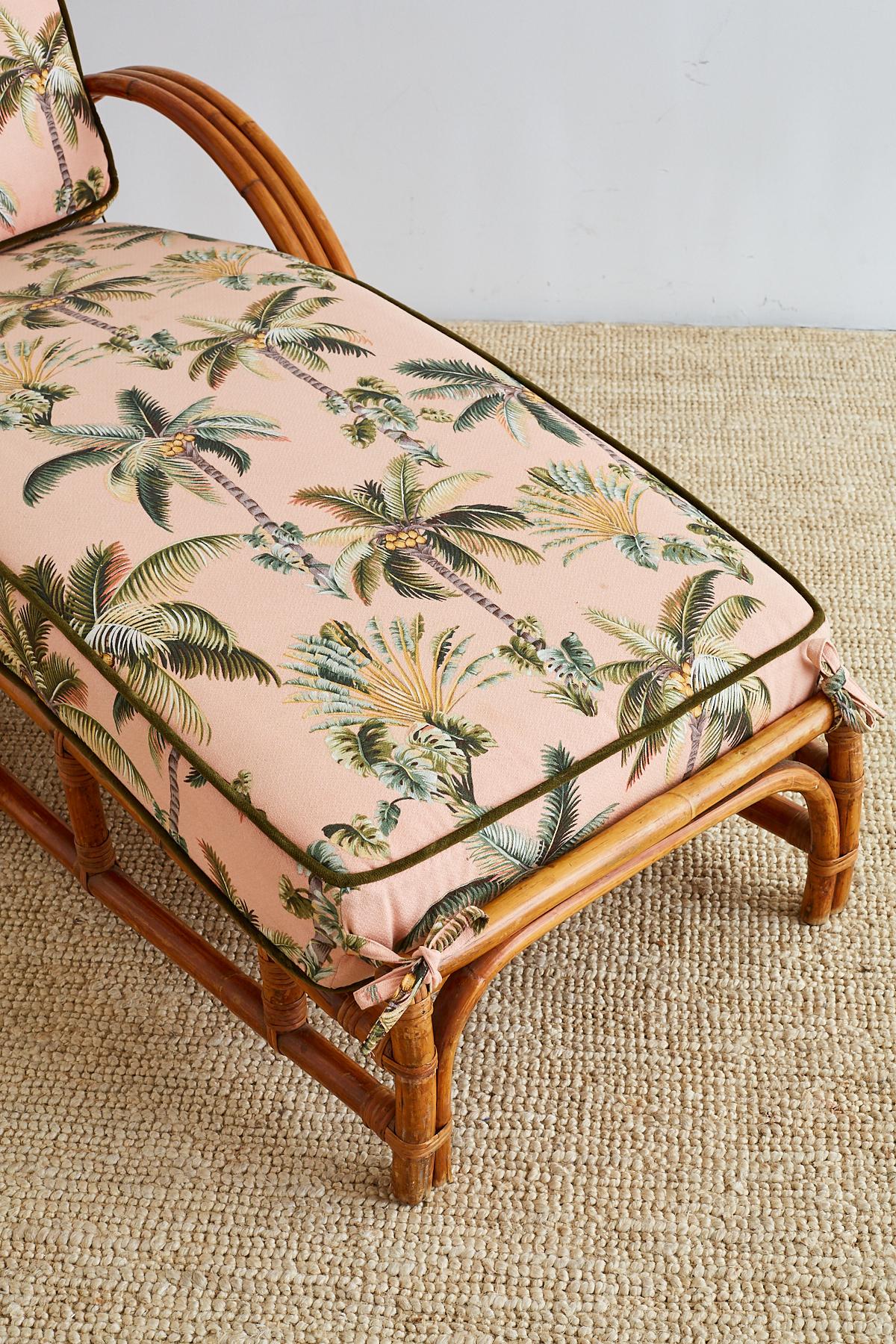 Festive three strand rattan chaise lounge or longue made in the manner and style of Paul Frankl. Authentic steam bent rattan frame supporting thick padded cushions with a Florida regency style fabric of palms. This Mid-Century Modern chaise is