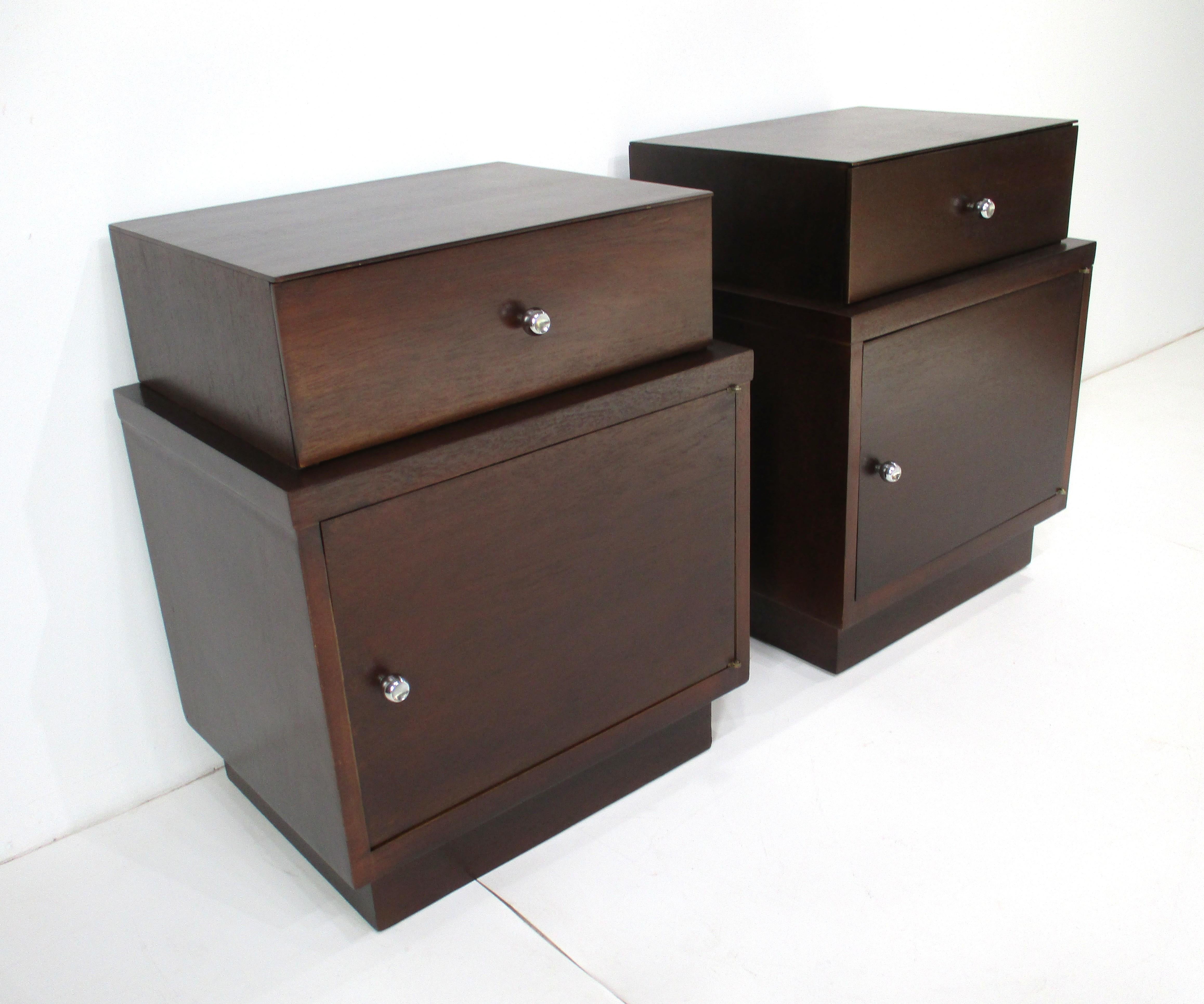 Paire de tables de nuit ou d'appoint Art Déco restaurées à la manière de Paul Frankl. Les tables de nuit ont un design empilable avec un tiroir supérieur et une porte inférieure avec rangement et des poignées chromées à fossettes rondes. Très bien