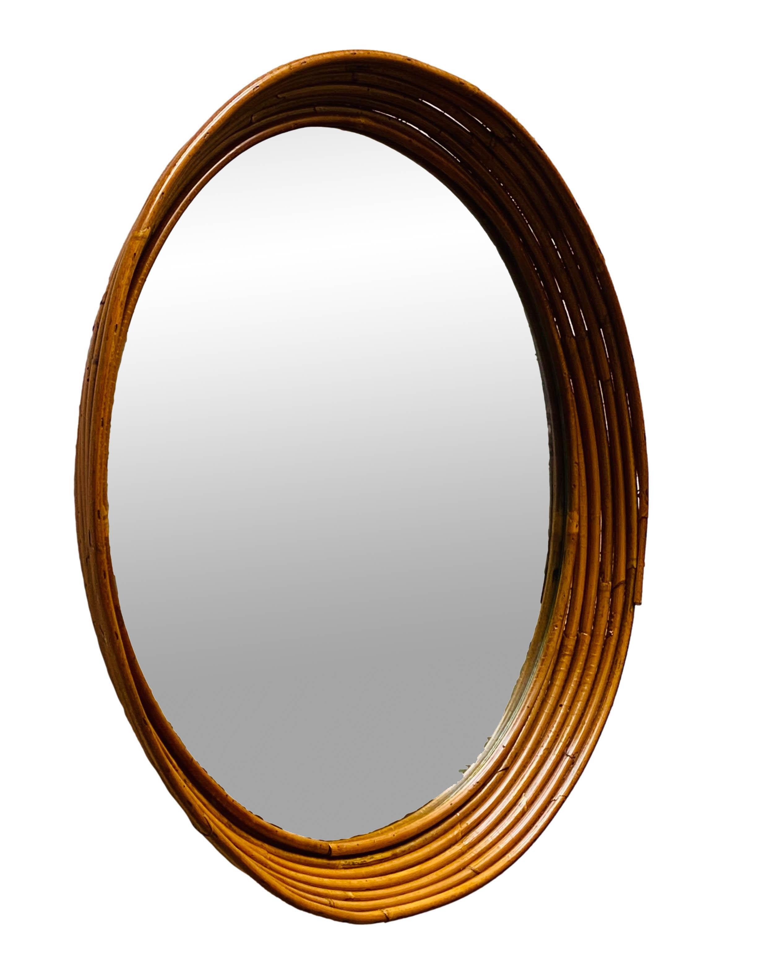 Stunning Italian rattan or bamboo wall mirror from the 1960s. The rounded frame is made of cane wicker with a mirrored glass insert. No trademark visible.