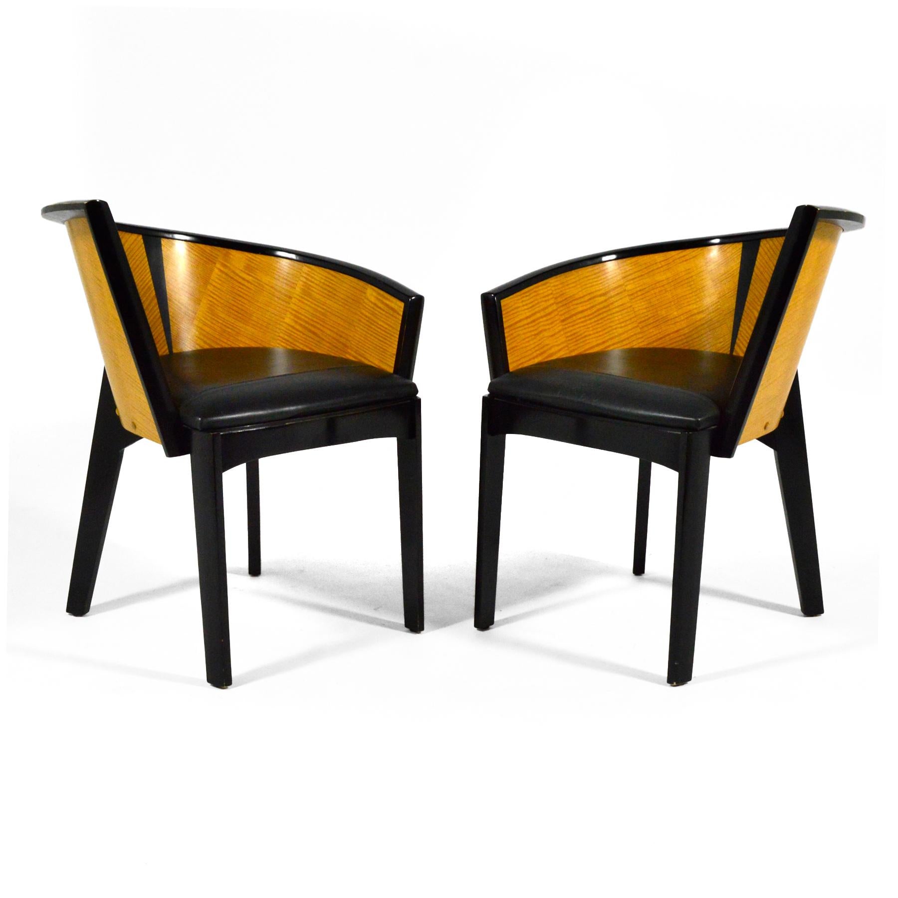 A combination of a side chair and a barrel chair, the Sinistra chair designed by Paul Haigh for Bernhardt in 1987 is a striking asymmetrical design. Rich wood veneers, black lacquered, and leather combine in this compelling Postmodern design that