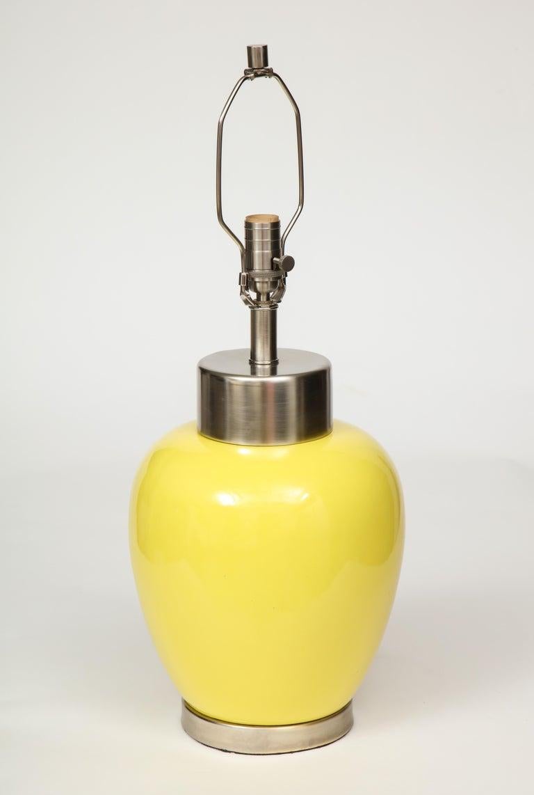 Pair of midcentury porcelain lamps with a lemon yellow glaze and brushed nickel hardware. 100W max bulbs. Rewired for use in USA.