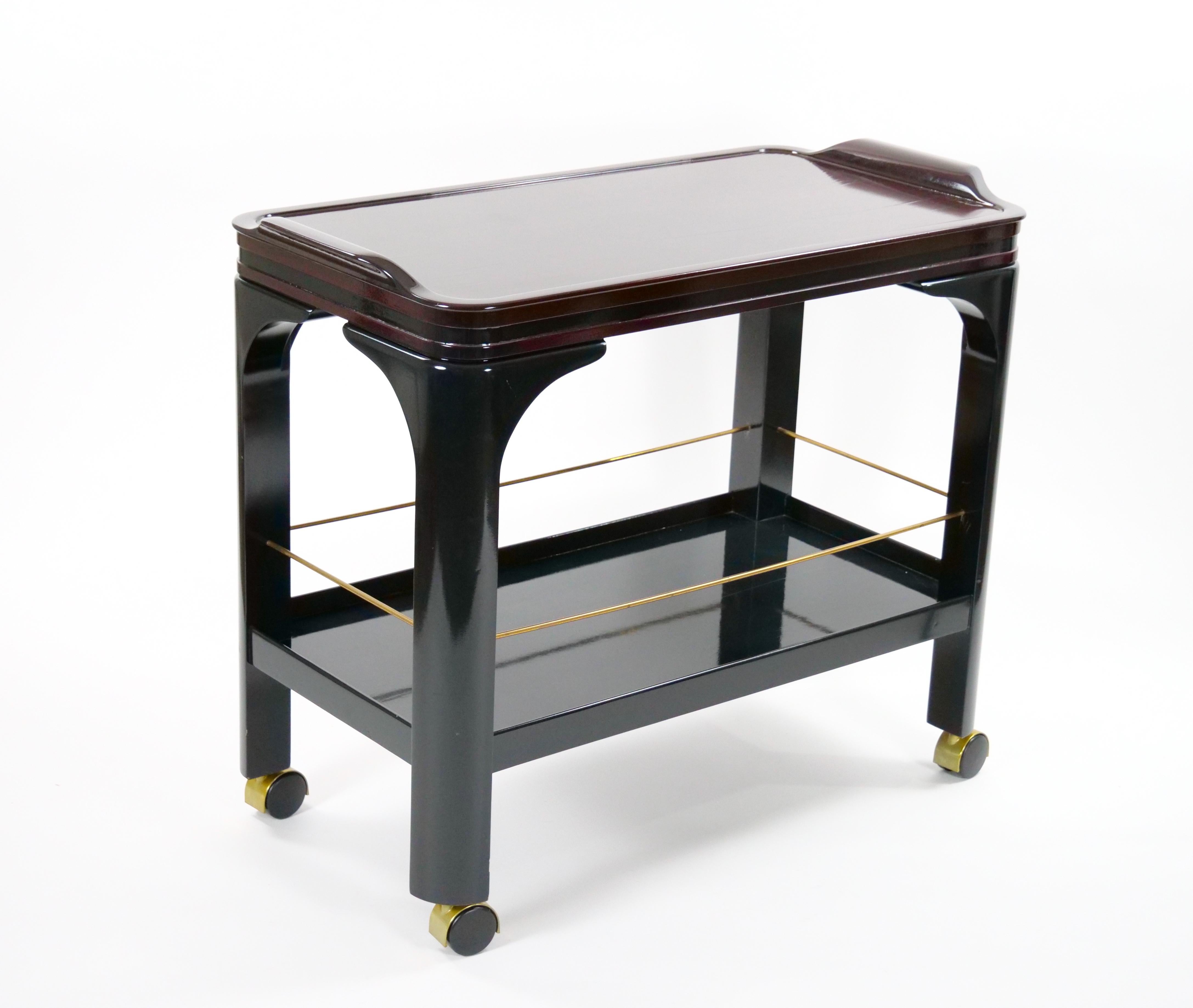 Elevate your entertaining with this stylish Mid-Century Modern Brown and Black Lacquered Two-Tiered Rolling Serving Bar Cart, showcasing exquisite brass accents and castor details on the lower shelf. Designed by the talented Paul M. Jones, this cart