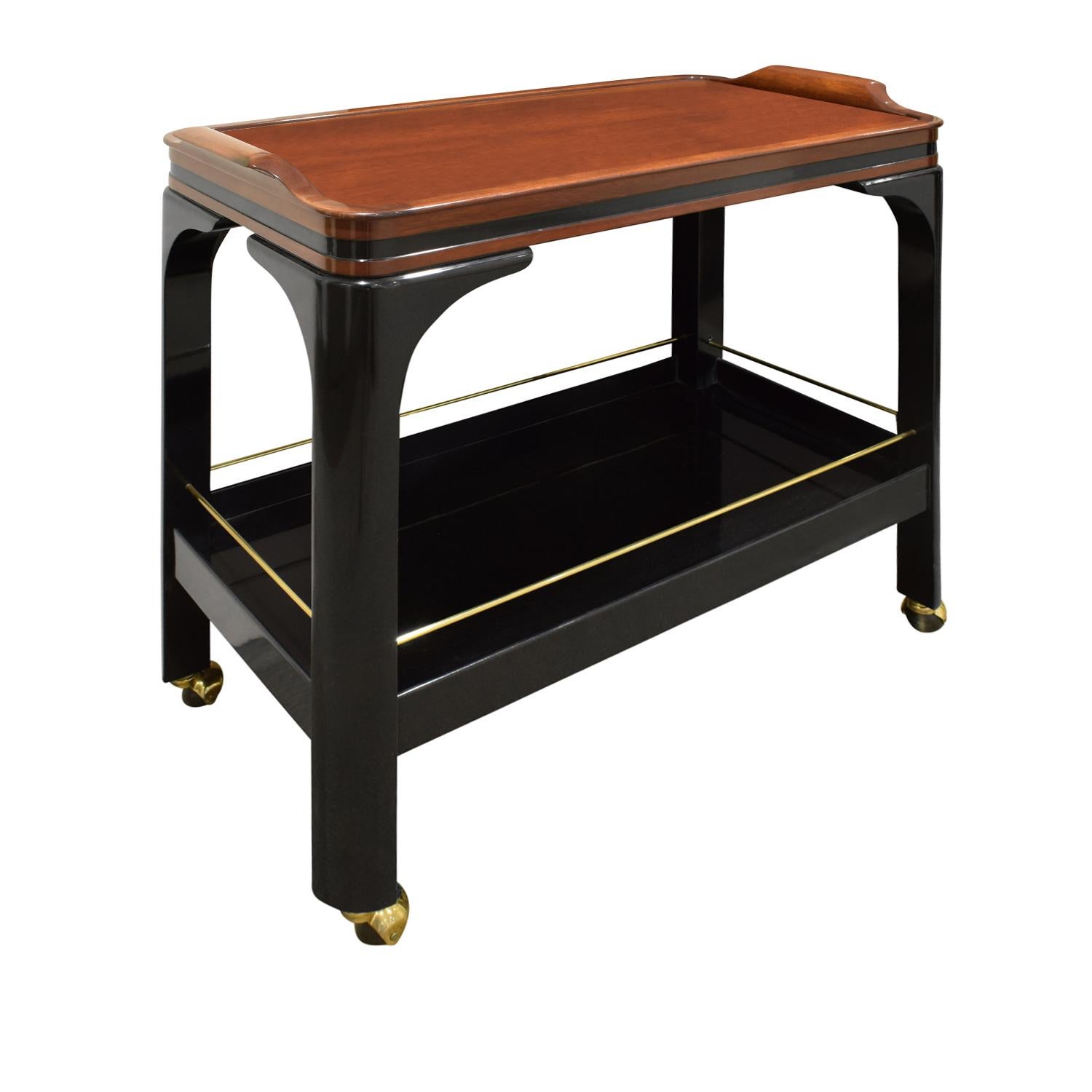 Rolling serving/bar cart model no. FM164 with black lacquer base and walnut top with brass accents and castors by Paul M. Jones, American 1960's.  This bar cart is beautifully made and very chic.