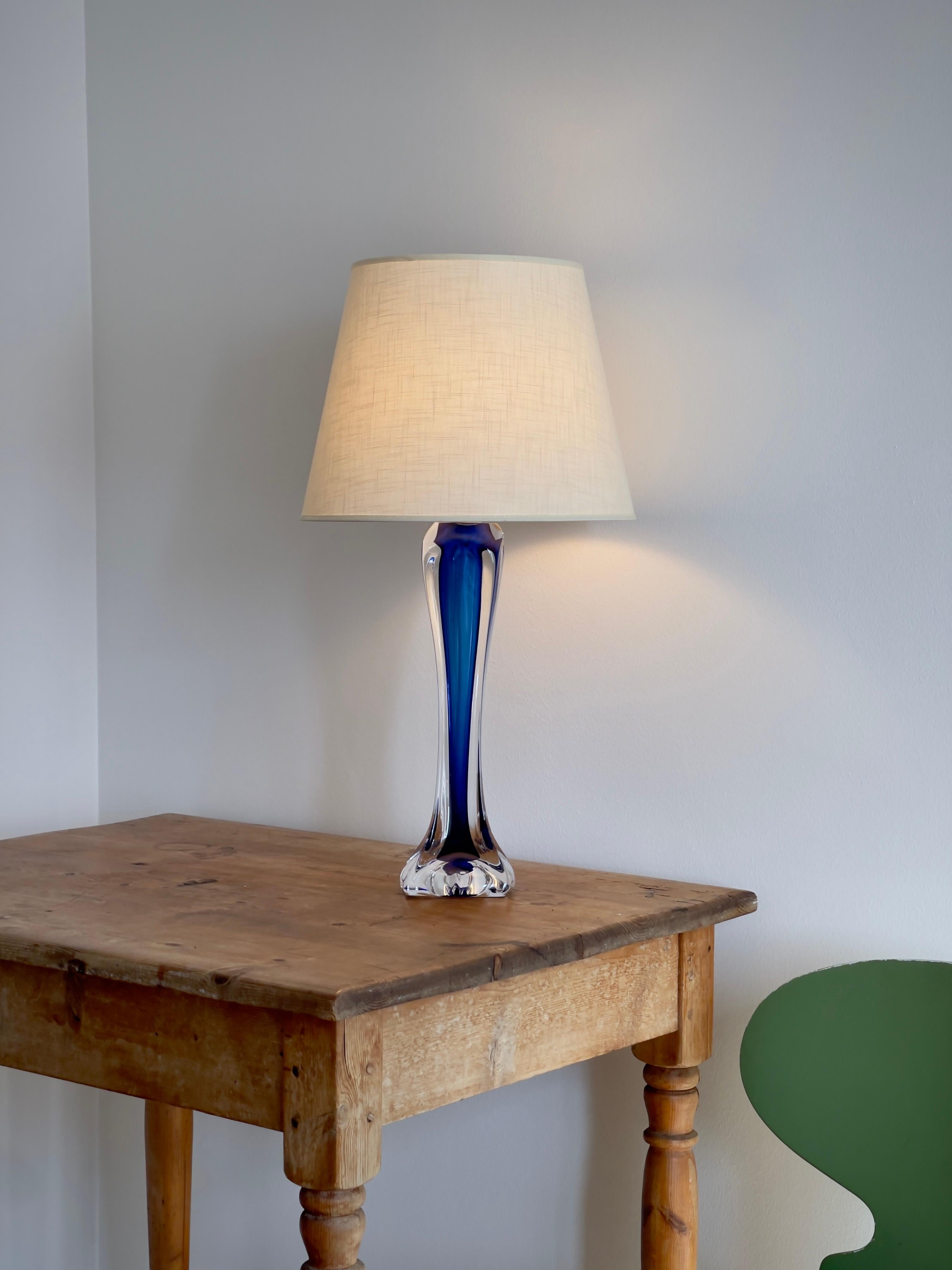 Conçue par Paul Kedelv pour Flygfors en Suède dans les années 1960, cette lampe de table étonnante illustre l'art raffiné du design en verre scandinave de l'après-guerre. Fabriquée en verre d'art lourd et solide, la lampe présente un cœur intérieur