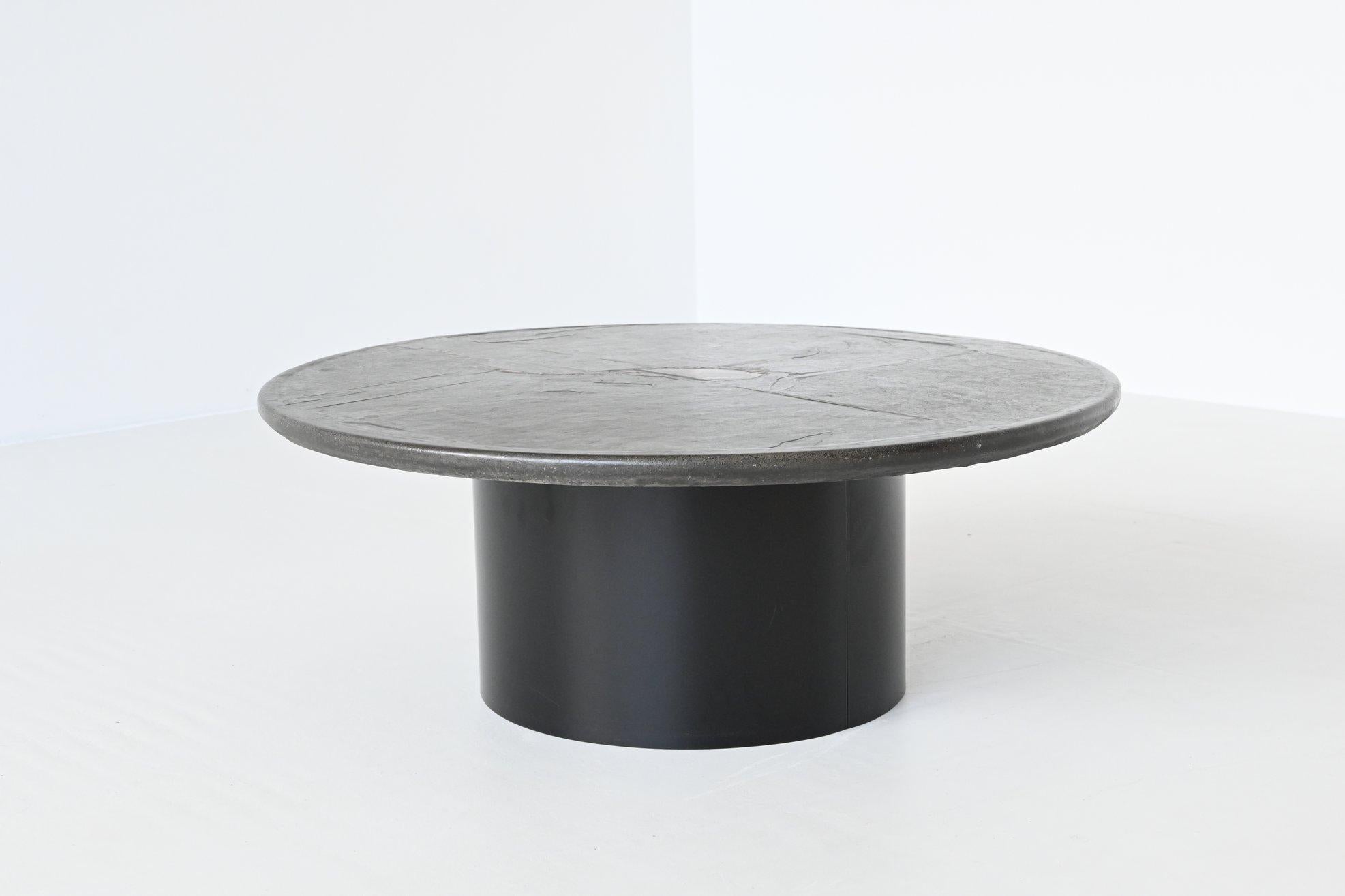 Beautiful round shaped coffee table designed and made by Paul Kingma, The Netherlands 1995. The dark colored heavy and thick concrete top rests on two metal C shaped bases that are black lacquered. Beautiful composition of slate, stones, copper and