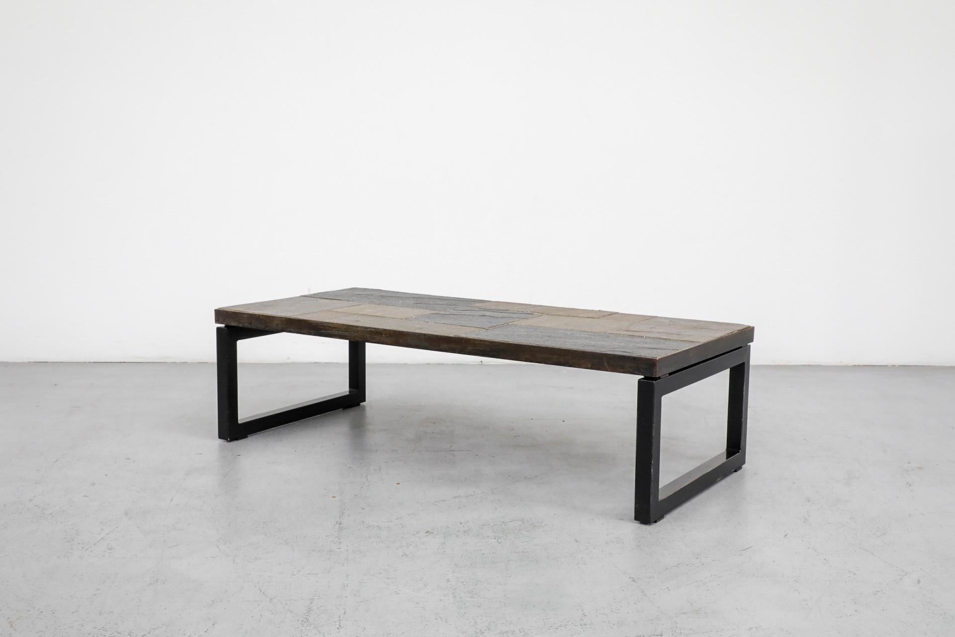 Stunning mosaic slate coffee table with banded metal frame. Extremely heavy, inlaid mixed slate pieces. In original condition with wear, including scratching to the stone and frame as well as minimal grout loss or loosening. Wear is consistent with