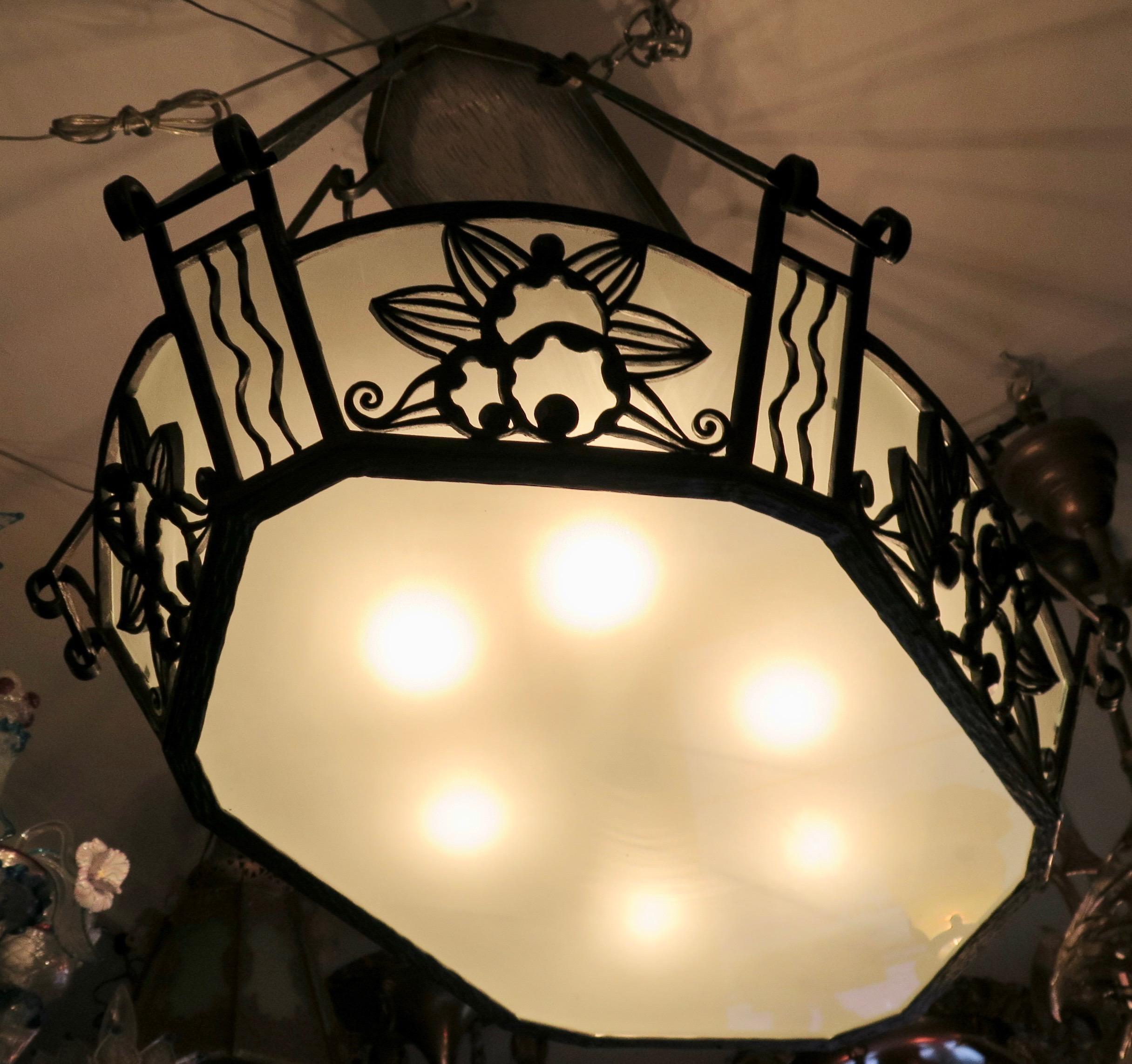 This vintage early 20th century is designed by Paul Kiss. It is a suspended fixture with a gondola like shape, designed with wrought iron metal work accented with frosted glass panels. There are four support arms that attach to a ceiling plate to
