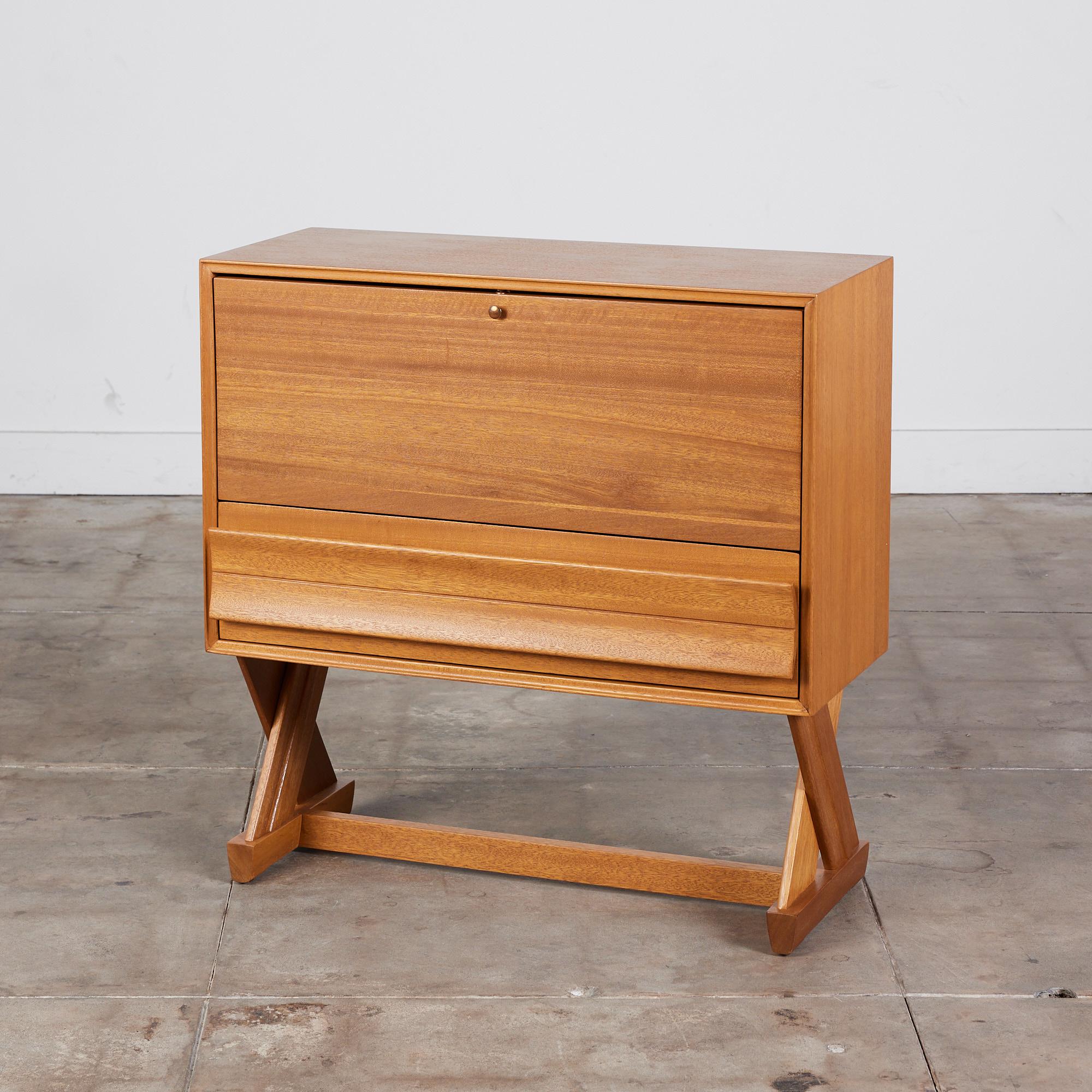 Bar cabinet by Paul Laszlo for Brown Saltman, c.1957. This cabinet features a mahogany body and X-shaped legs with a pull down front. The top portion features vertical separation and lower storage drawer. The front panel drops down and can be used