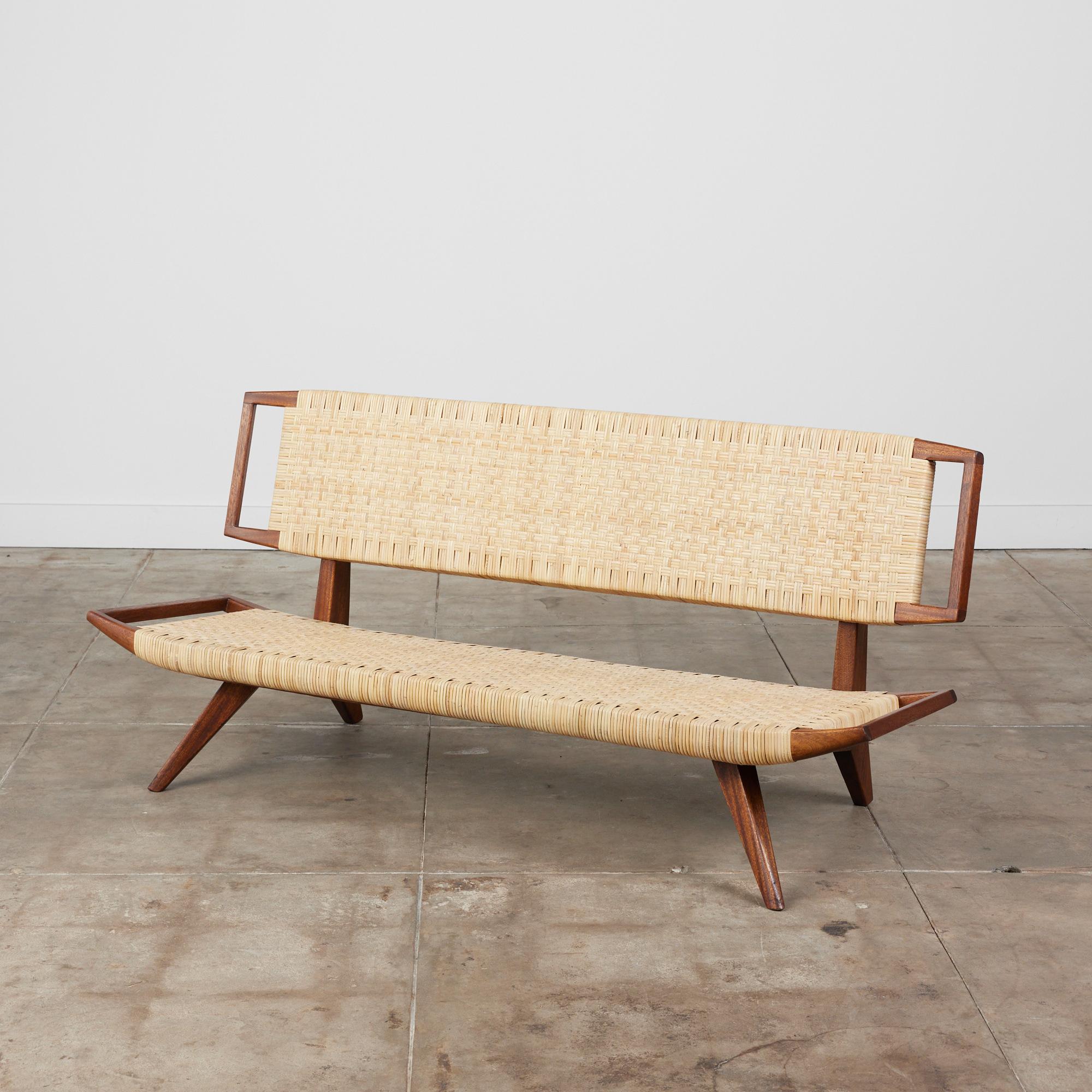 Rare museum grade bench by Paul Laszlo for Glenn of California, c.1950s. The bench features an oiled mahogany frame with newly woven cane seat and back. The woven seat lays atop the frame that is supported by outwardly pitched legs. The frame serves