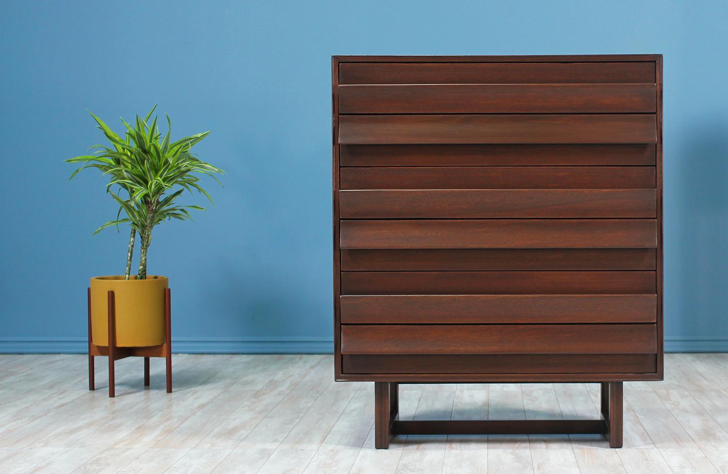 Stunning chest of drawers designed by Paul Laszlo for Brown Saltman and manufactured in the United States circa 1950’s. This graceful chest design features a dark walnut-stained mahogany frame with a geometric base. The unique sculpted fin-like