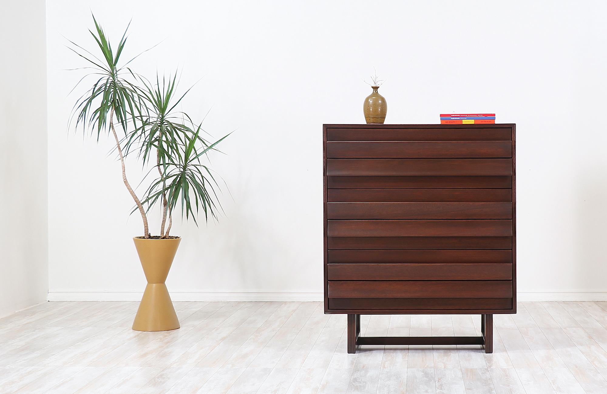 Stunning chest of drawers designed by Paul Laszlo for brown Saltman and manufactured in the United States, circa 1950s. This graceful chest design features a dark walnut-stained mahogany frame with a geometric base. The unique sculpted fin-like
