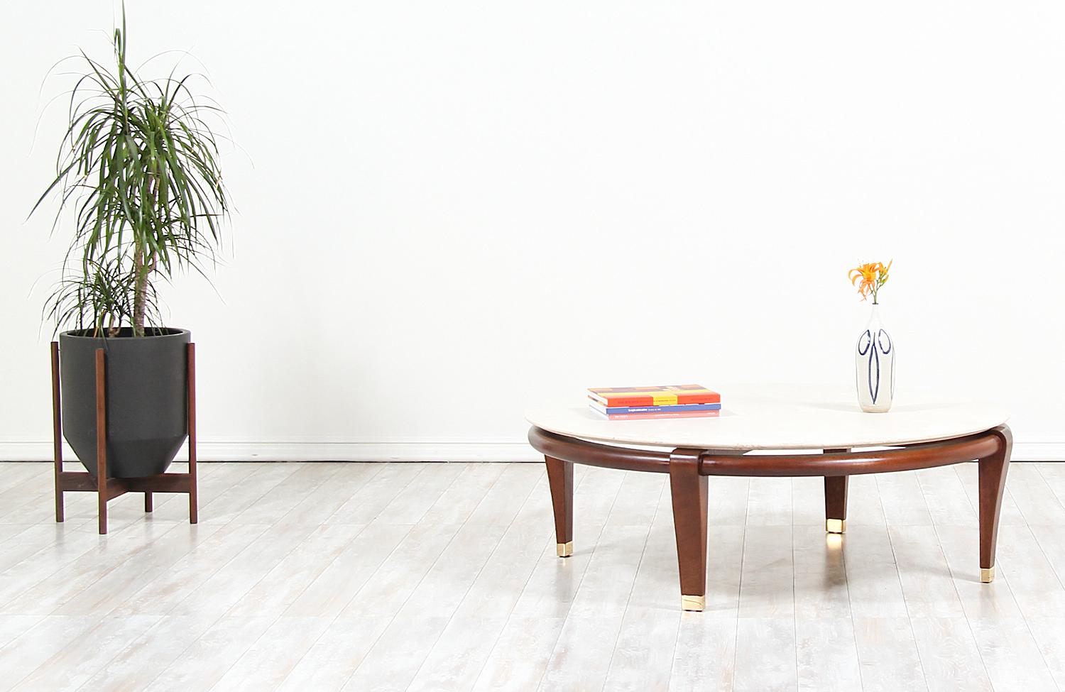Beautiful model 145 modern coffee table designed by Paul Laszlo for Brown Saltman in the United States, circa 1950s. This iconic design features a walnut stained mahogany base with beautifully sculpted legs and brass sabots. The circular floating