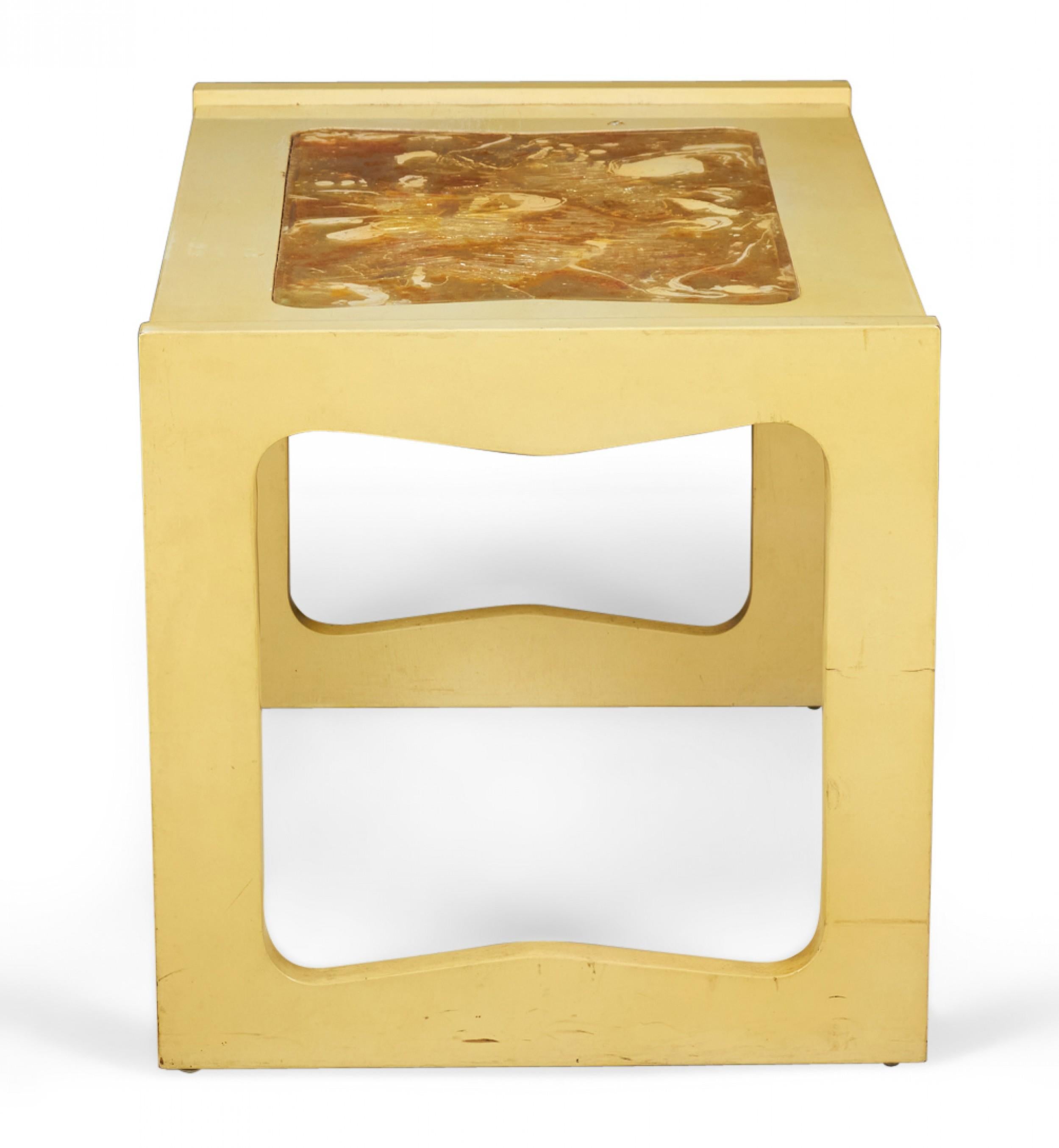 Mid-Century Modern end / side table with a beige painted wooden frame and rectangular top with an inset abstract gold, red, and orange resin center, supported on either side by two square legs with scalloped interiors. (PAUL LASZLO FOR BROWN SALTMAN)