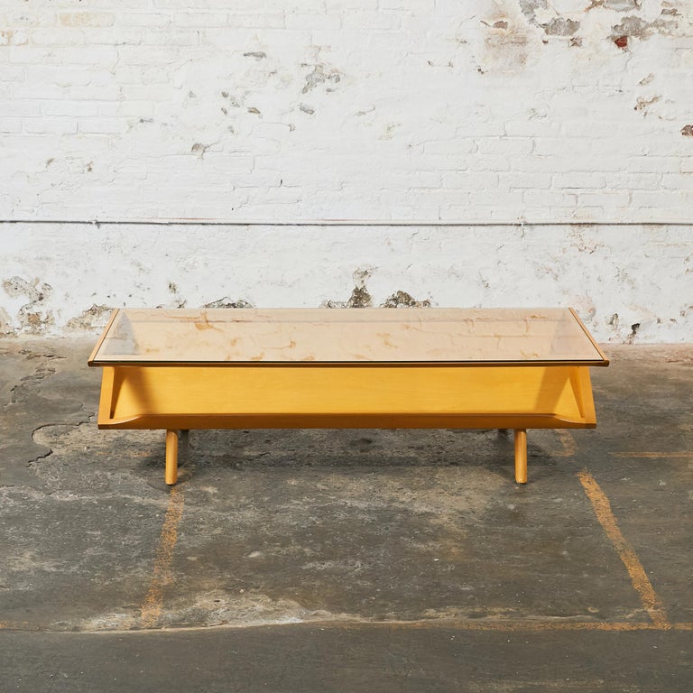 Long rectangular midcentury coffee table. The top frame holds a clear glass insert to see through the angled lower display shelf.
A Classic design by Paul Laszlo for the prominent California design company Brown Saltman.