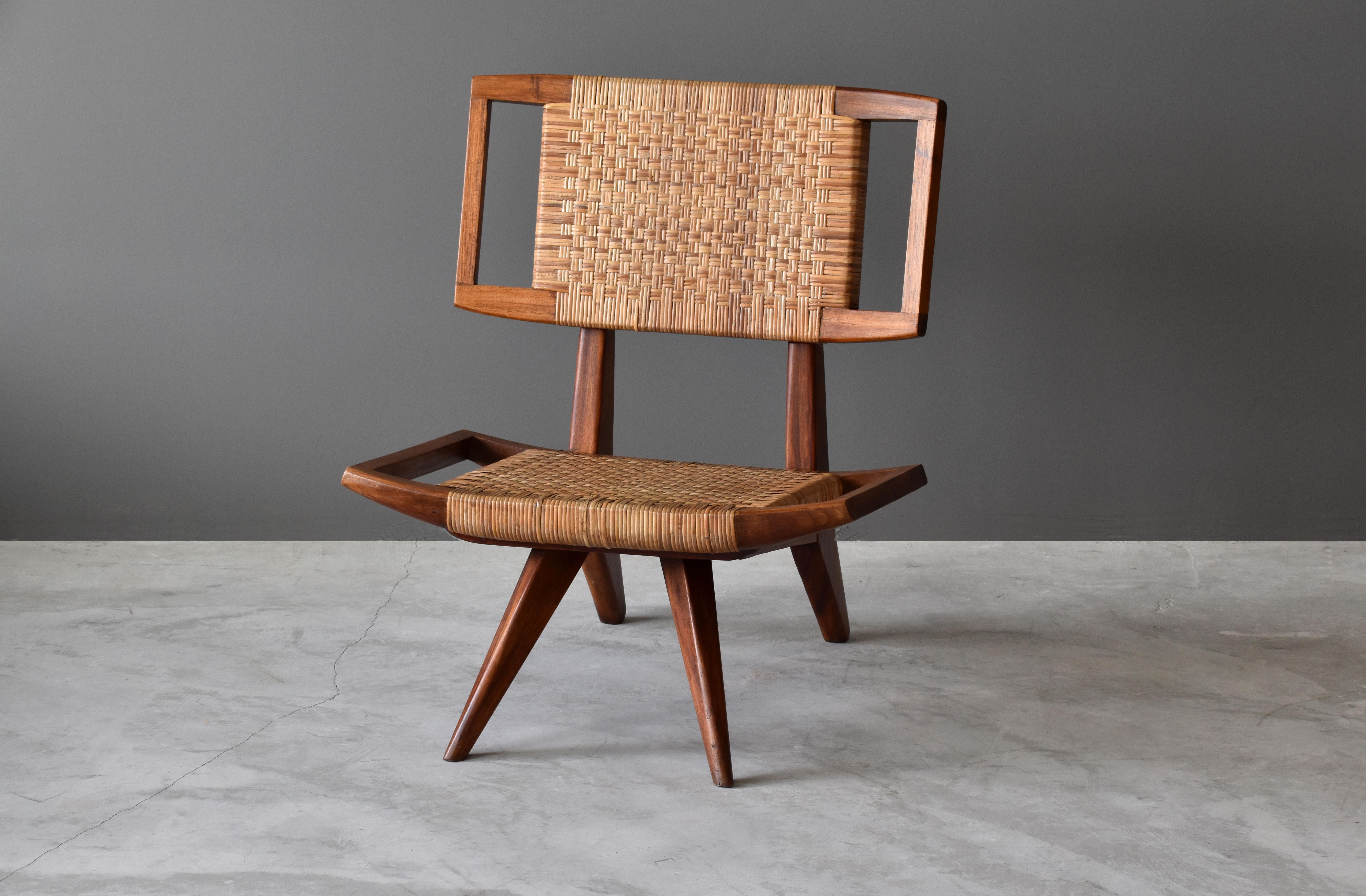 A lounge chair / slipper chair by Paul László for Glenn of California. Dark stained mahogany and original woven rattan / cane seat and back.

Paul László is considered among the most important California-based interior designer/architects of all
