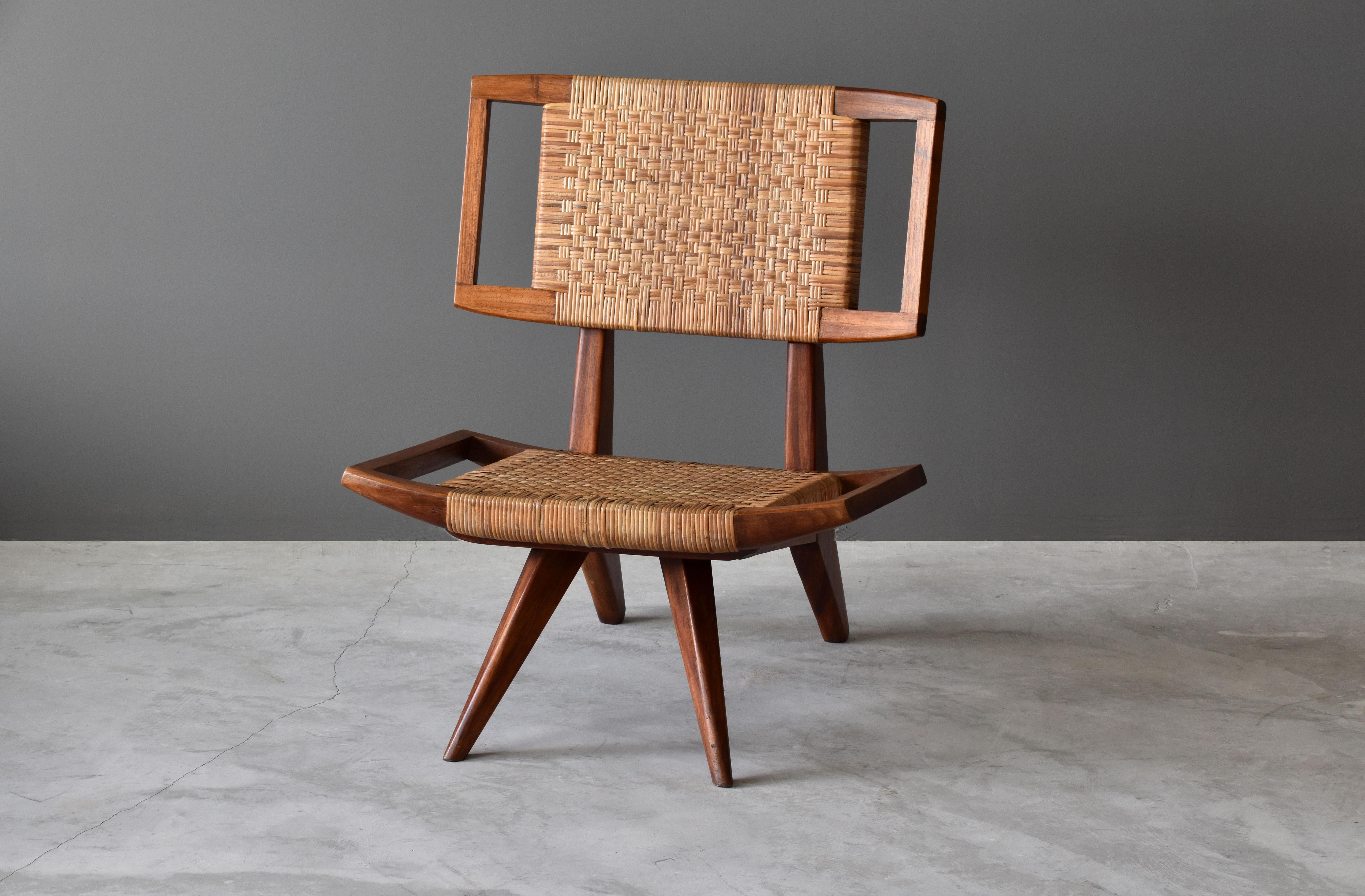 A lounge chair / slipper chair by Paul László for Glenn of California. Dark stained mahogany and original woven rattan / cane seat and back.

Paul László is considered among the most important California-based interior designer/architects of all
