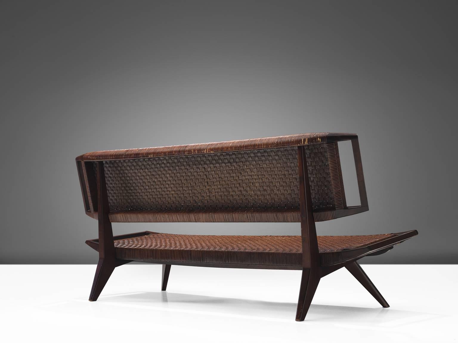 Paul László for Glenn of California, settee, cane and mahogany, United States, 1950.

This sofa by Paul László is designed with a caned back and seat that is in good patinated condition. The legs of the sofa are pointed outwards and feature
