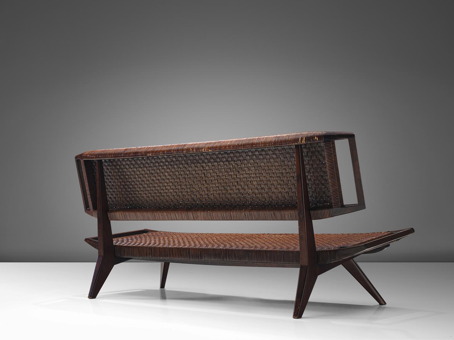 Paul László for Glenn of California, settee, cane and mahogany, United States, 1950.

This sofa bench by Paul László is designed with a caned back and seat that is in good patinated condition. The legs of the sofa are pointed outwards and feature
