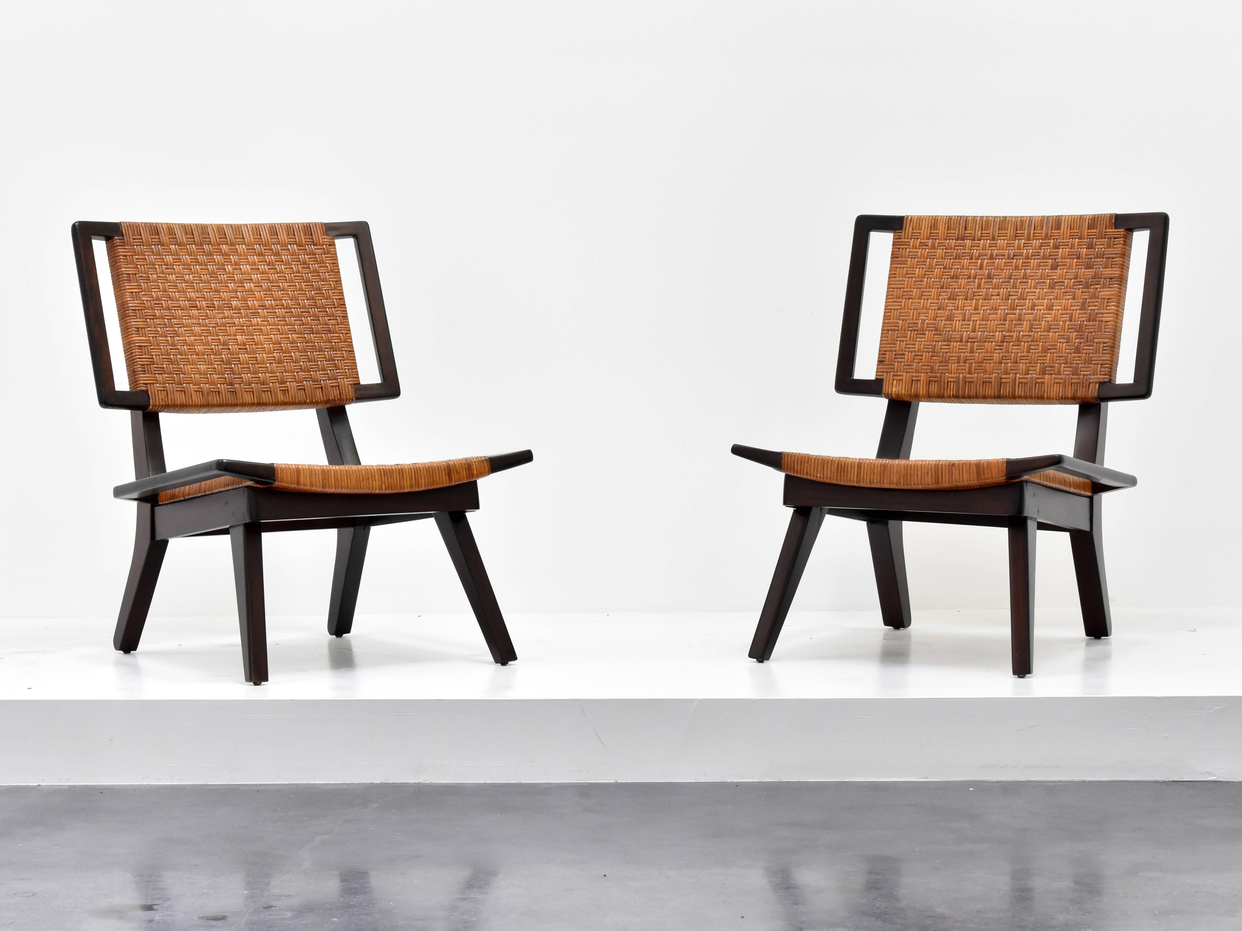 A pair of lounge chairs in the style of Paul László for Glenn of California. Dark stained mahogany and original woven rattan. Two pairs are available, as well as a settee. 

Paul László is considered among the most important California-based